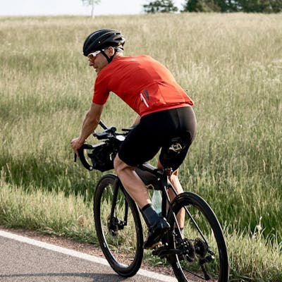 Road cyclist biking along a field