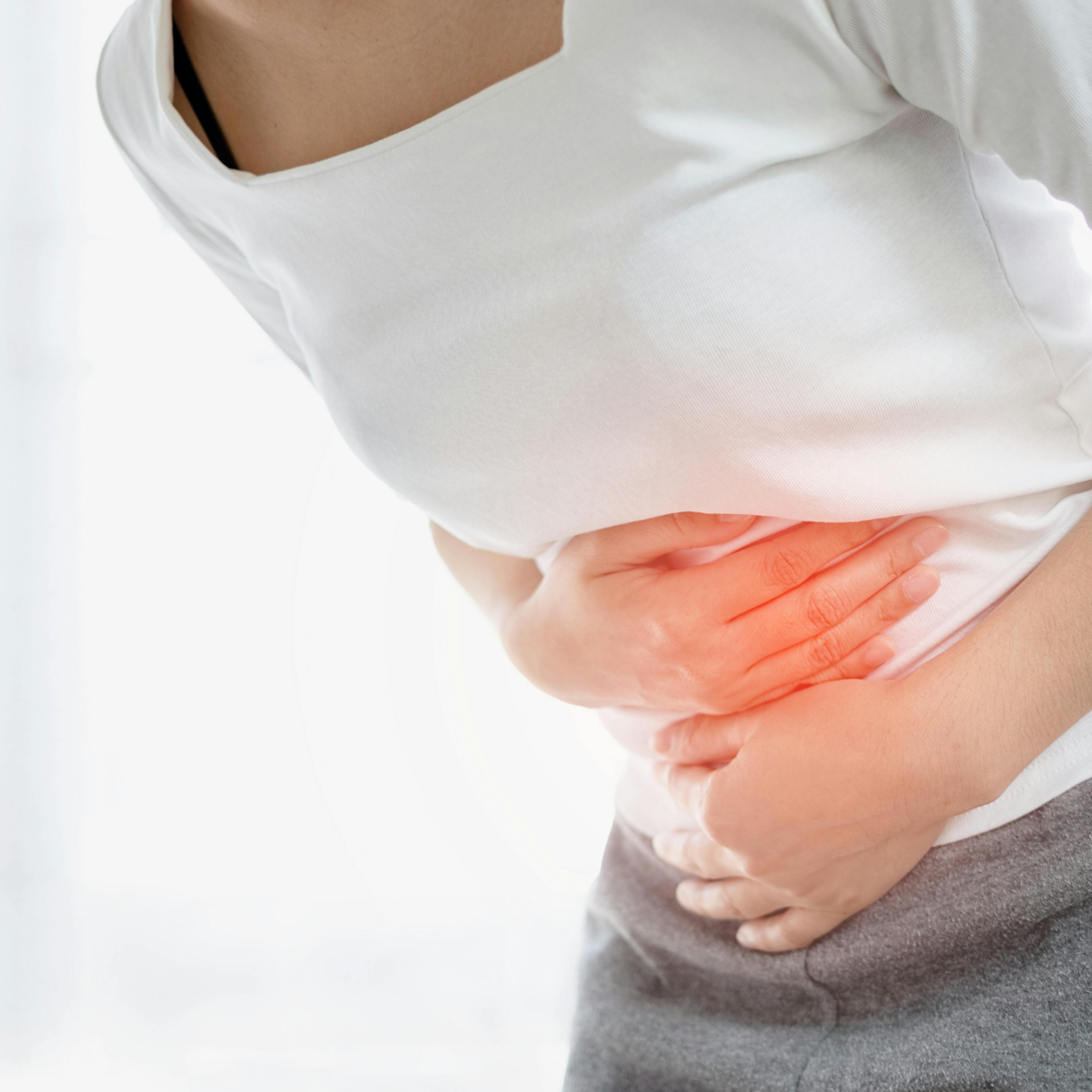 Young woman holds her stomach in discomfort