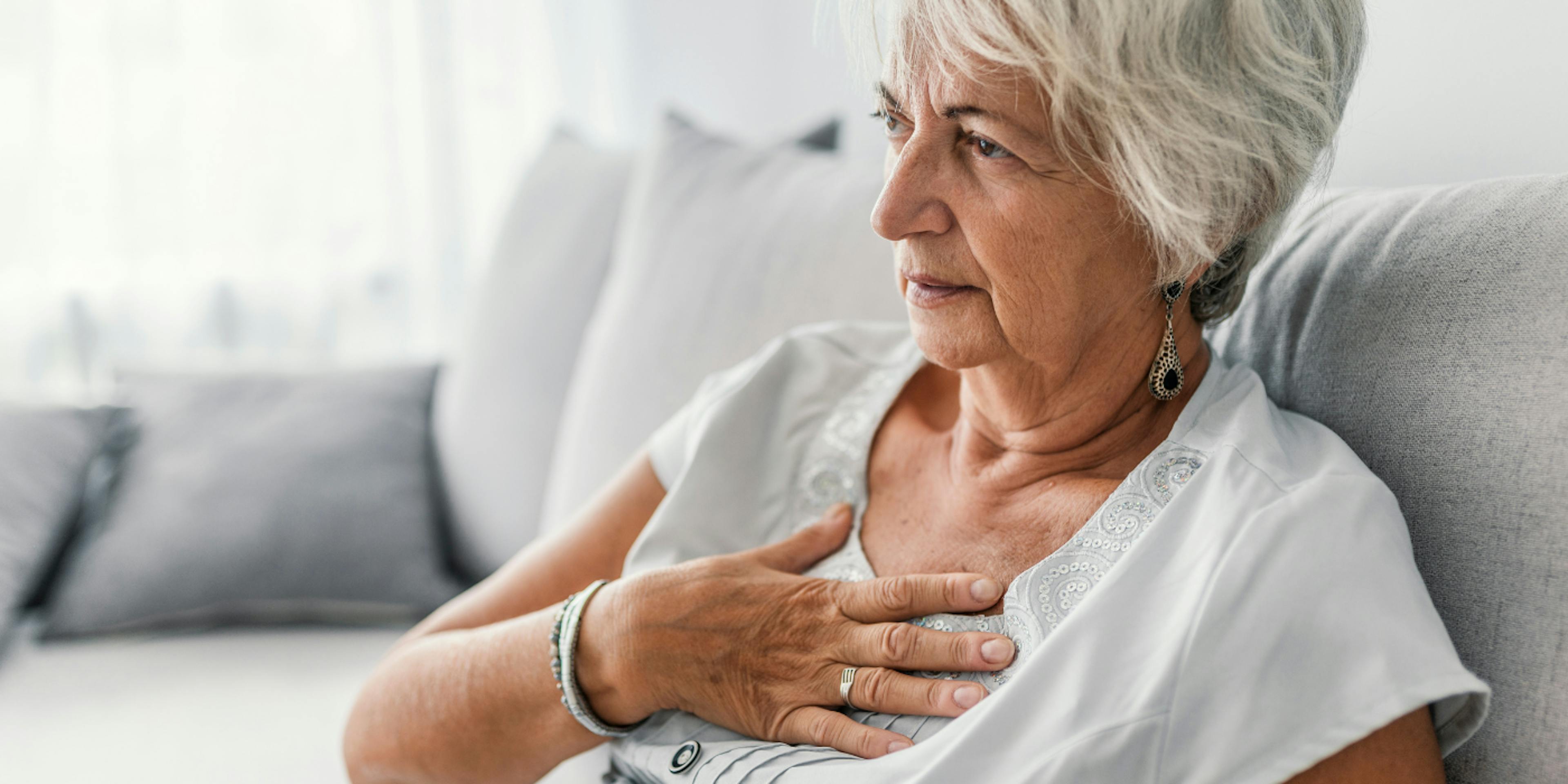 Elderly woman holding her chest in discomfort