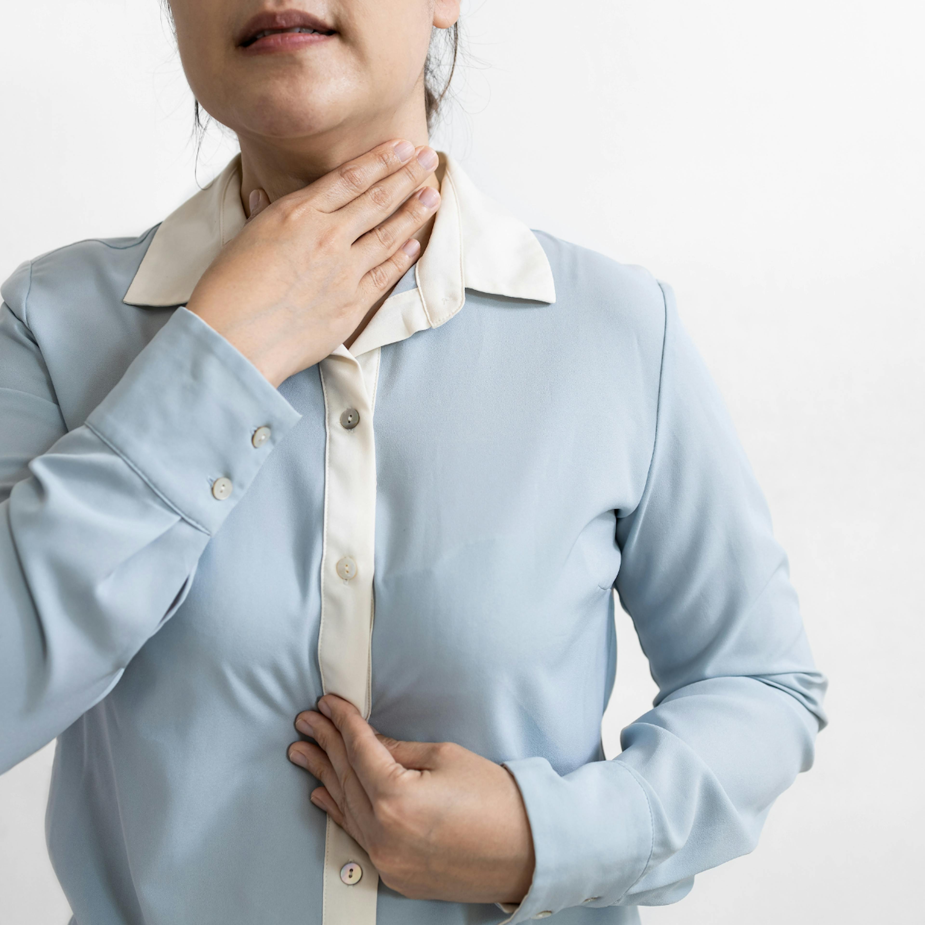 A woman holds her throat fearing regurgitation