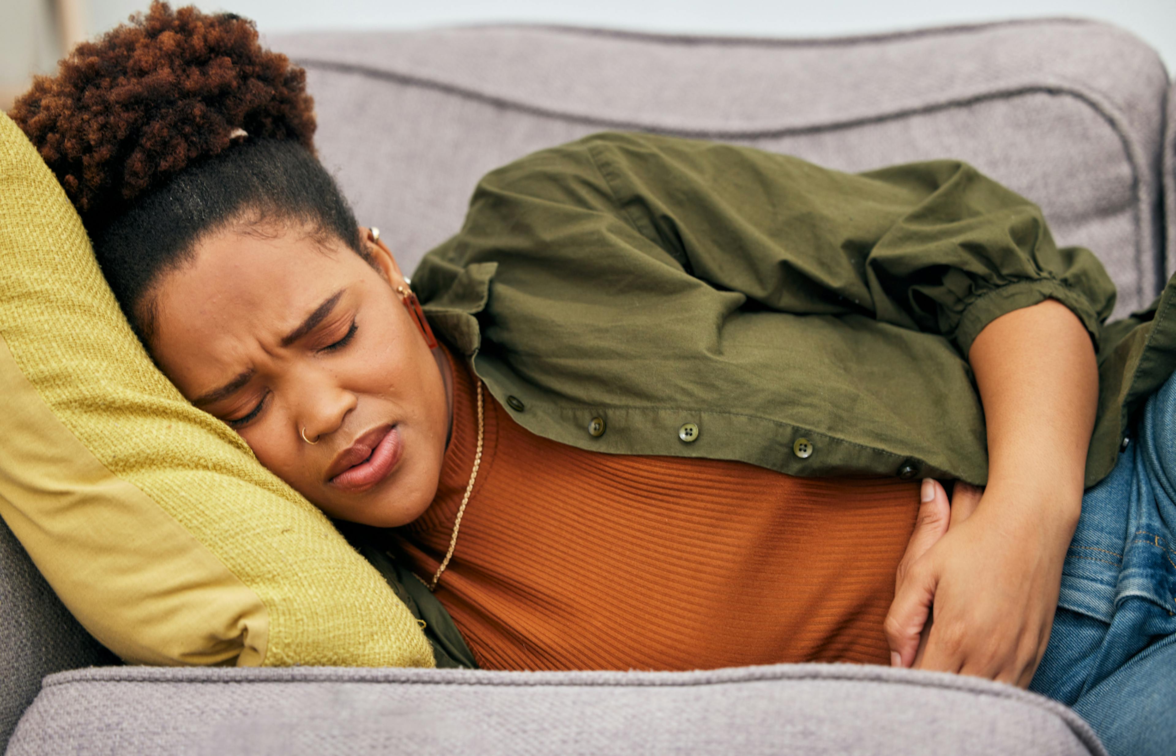 Young woman laying down with acid reflux bloating aches