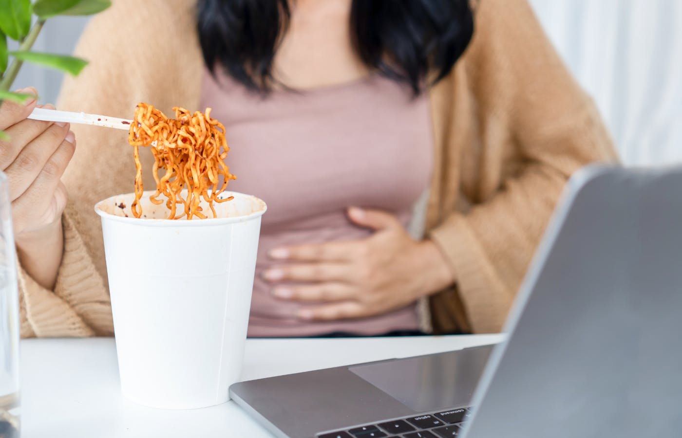 A woman experiencing GORD/GERD symptoms whilst eating pasta