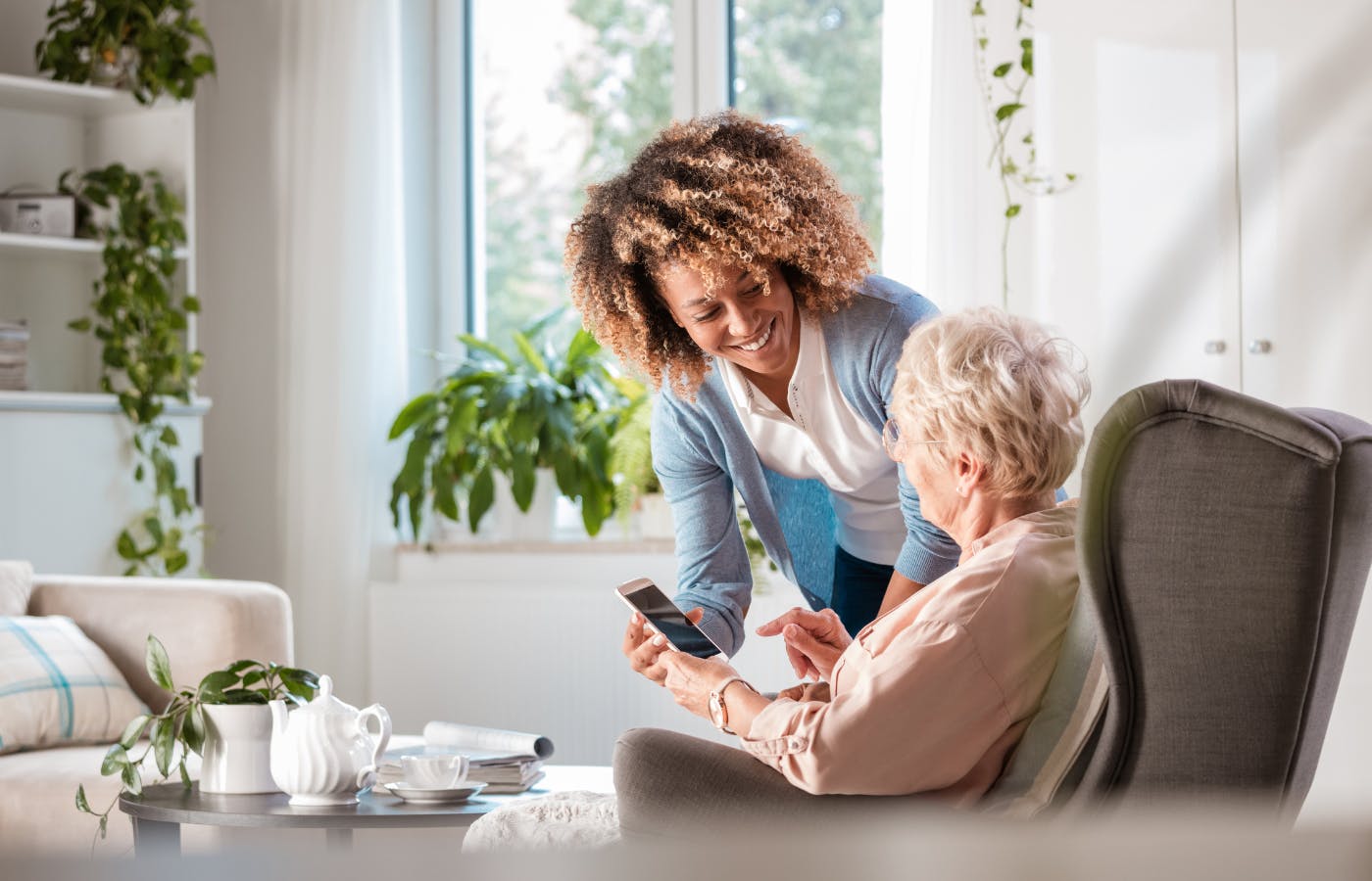 A woman helping an elderly women with her phone