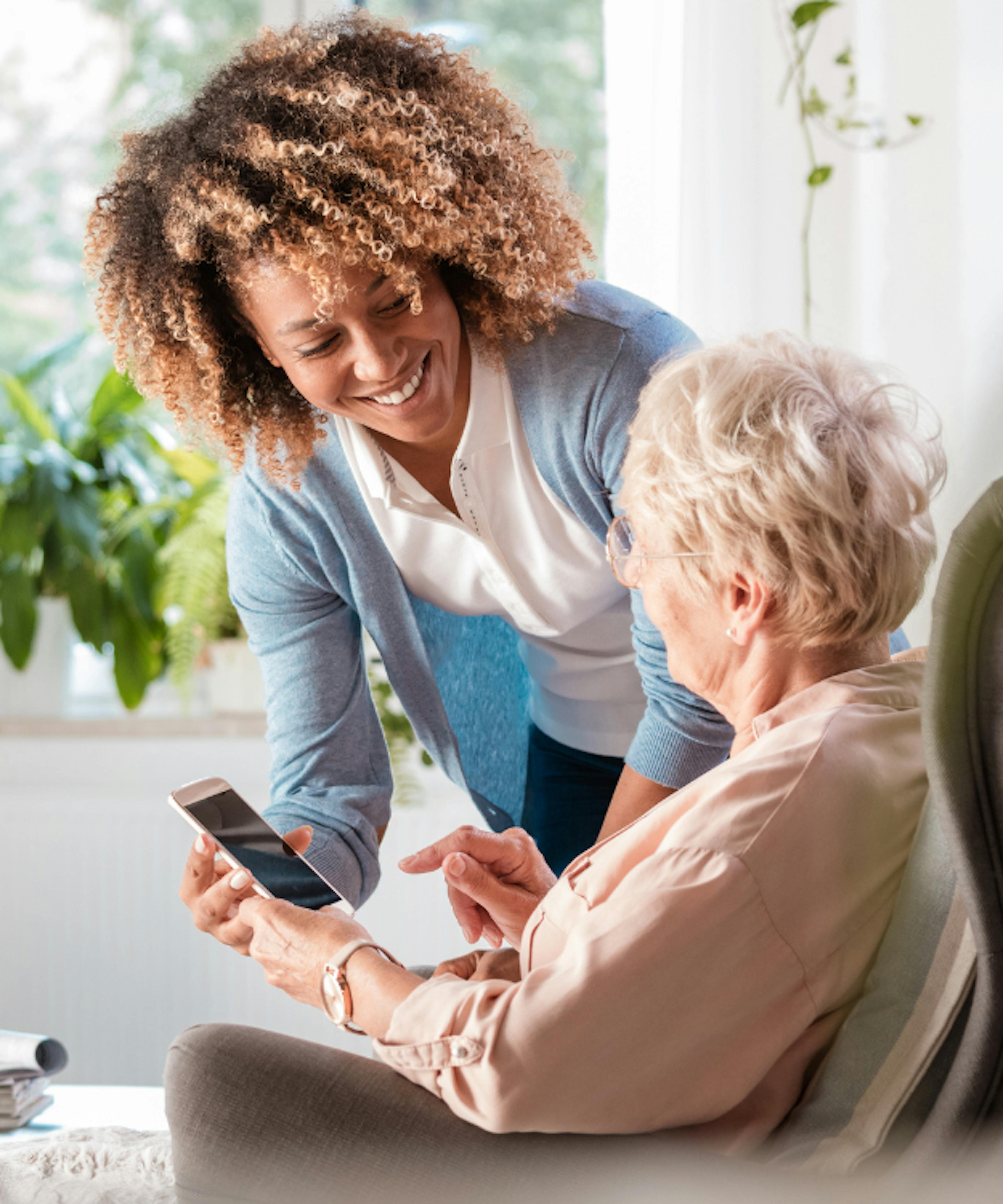 A woman helping an elderly women with her phone