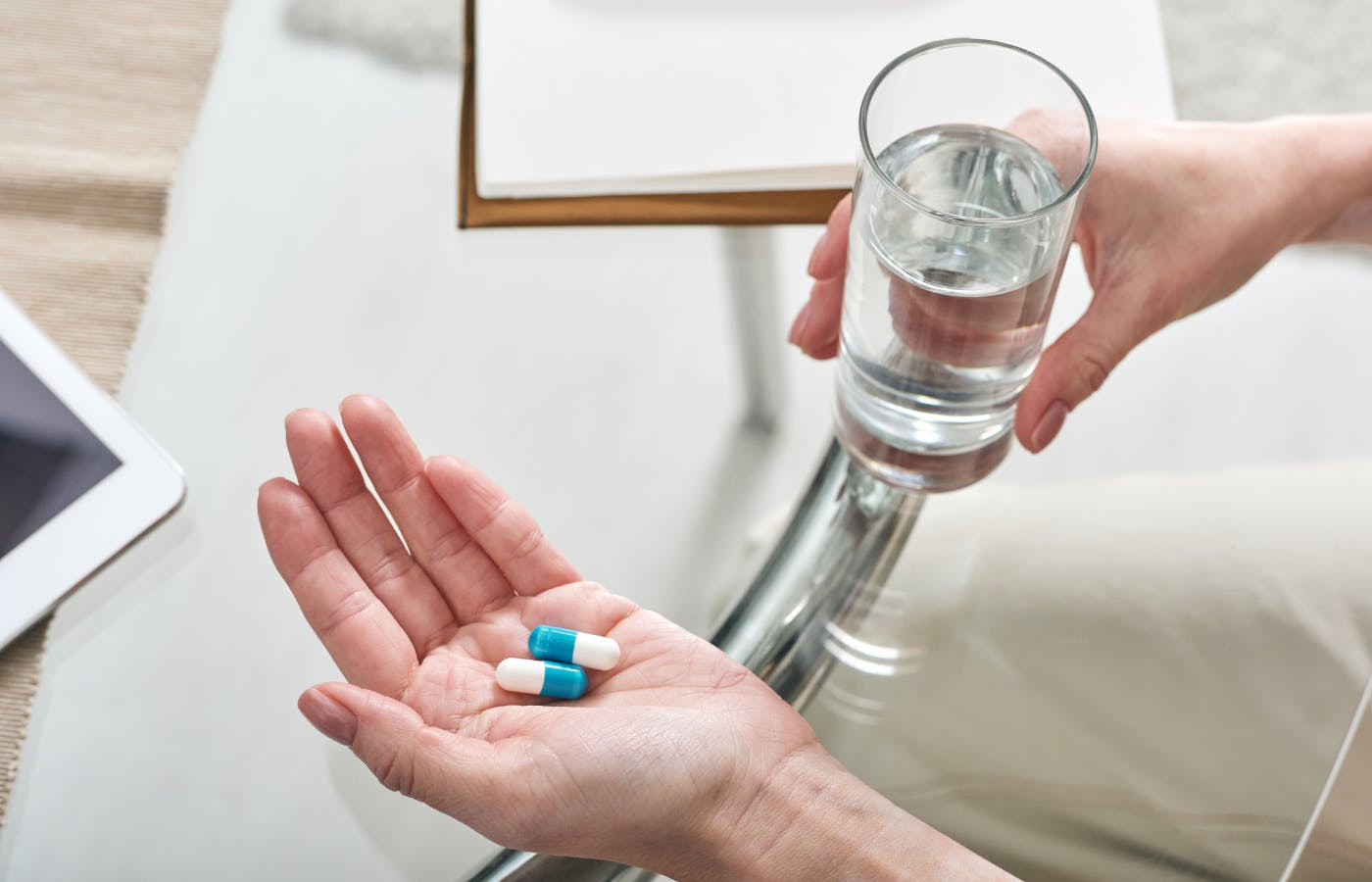 person holding pills and a glass of water