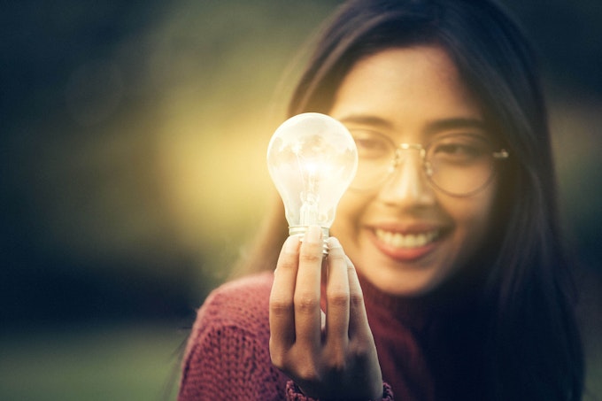 Woman happily holds an illuminated light bulb