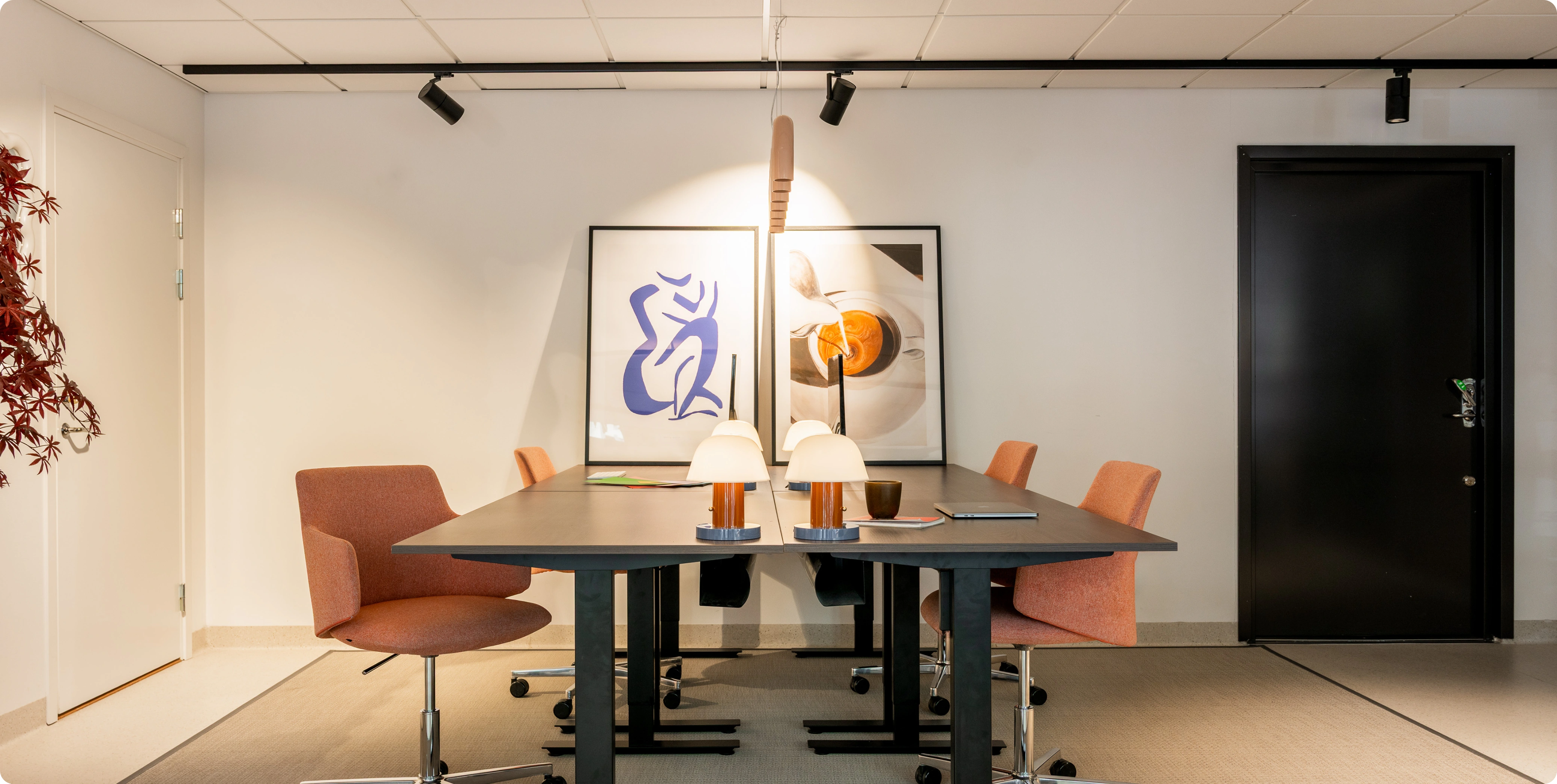 Work area with desks, chairs, lamps, and framed art on the wall.