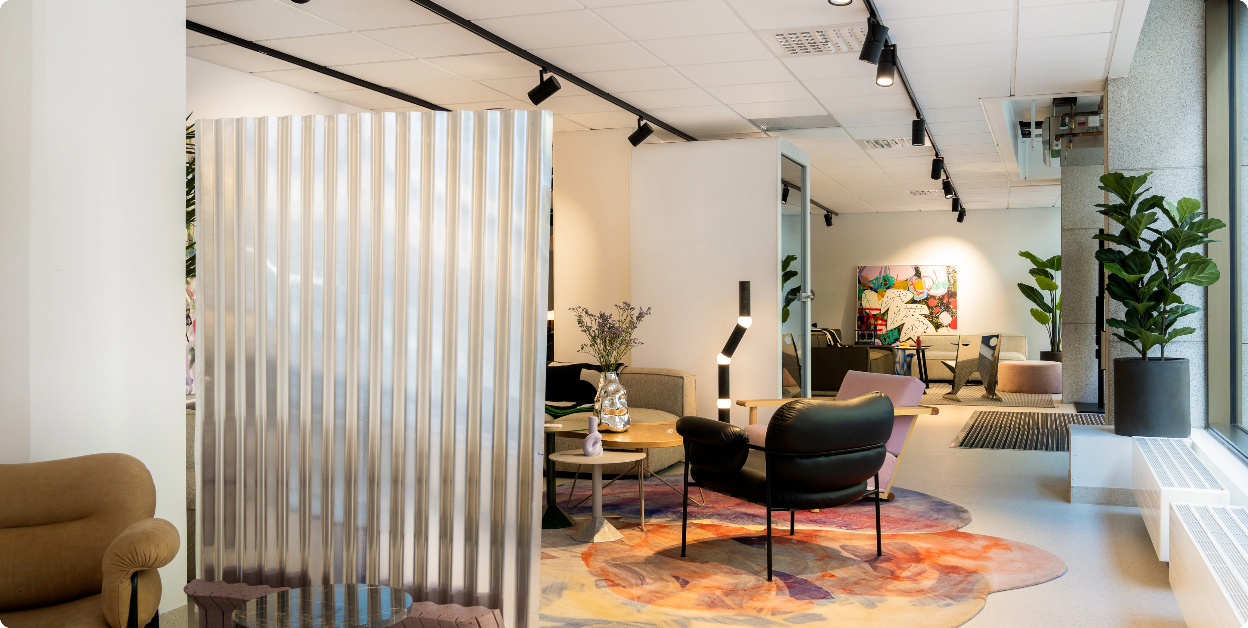 Lounge area with sofas, chairs, rug, wall art, a divider, and plants.