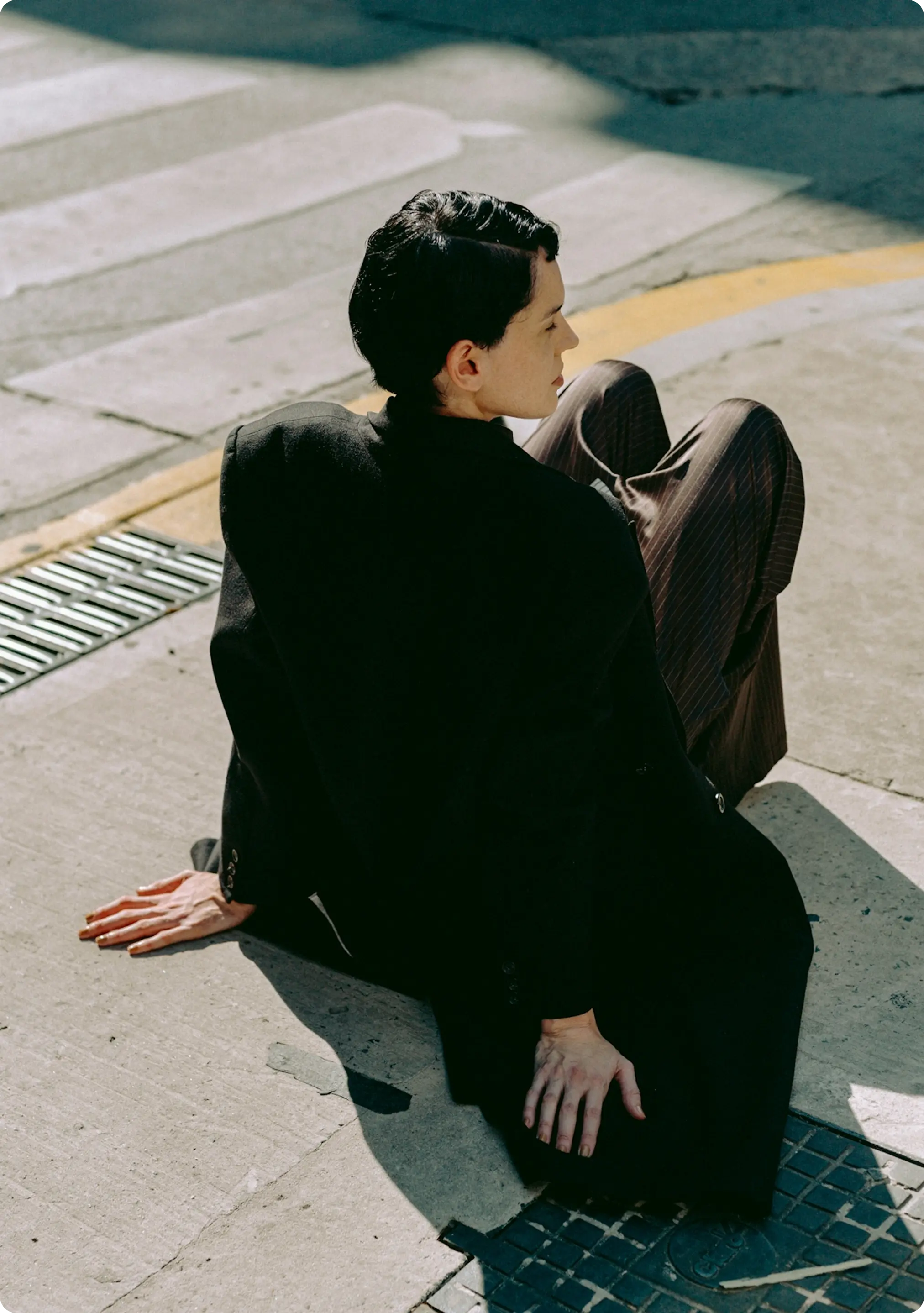 Person in a black blazer sitting on the pavement – symbolising change and reflection in working life.