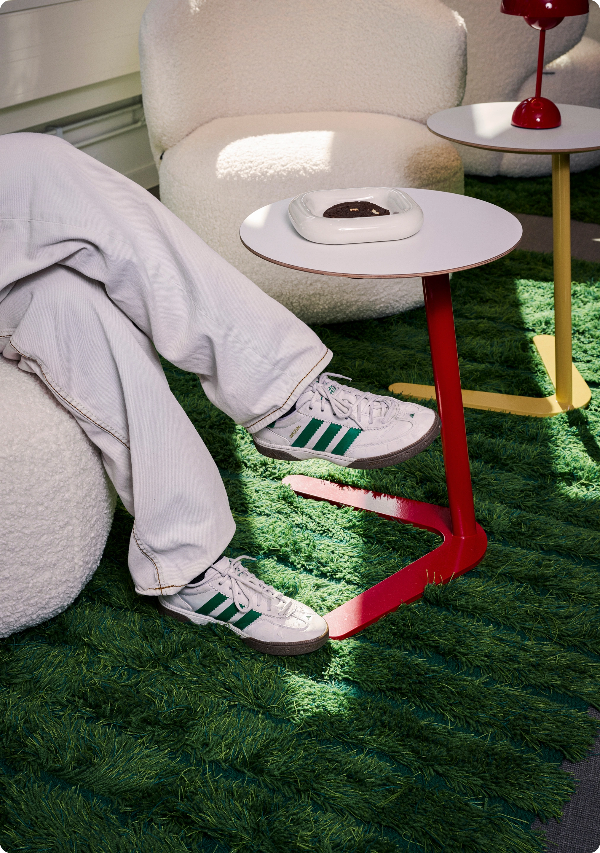 Detalj av person i sneakers som sitter i loungefåtölj bredvid småbord i Kings kontor.