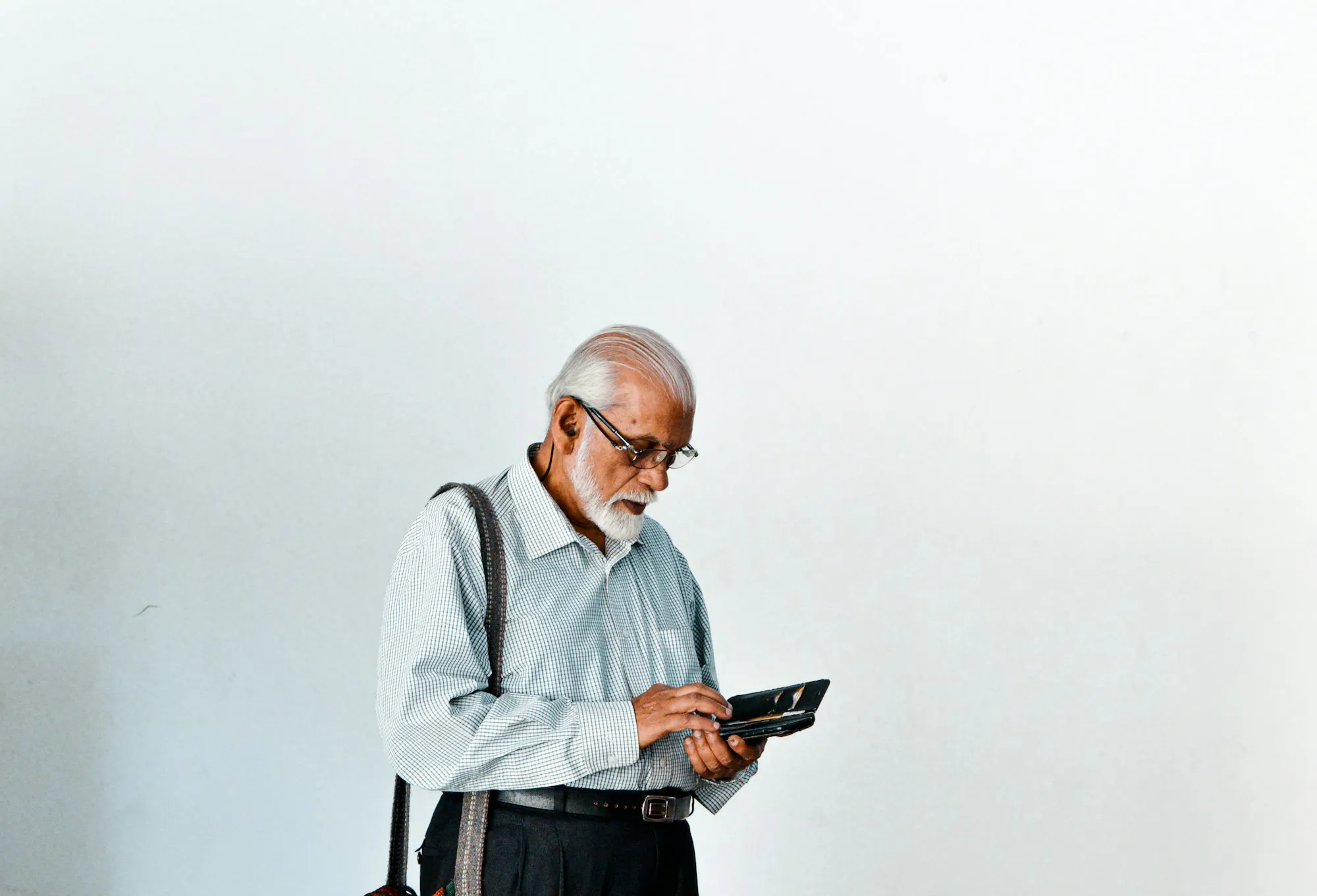 Older South Asian man looking closely at a tablet screen, as when checking progress from digital rehab exercises