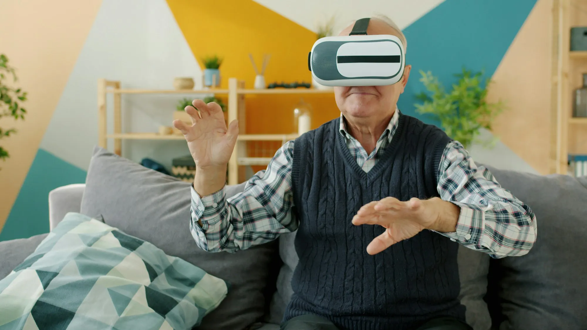 Older man wearing a virtual reality headset and reaching forward with both hands, the kind of movement practised in VR rehabilitation