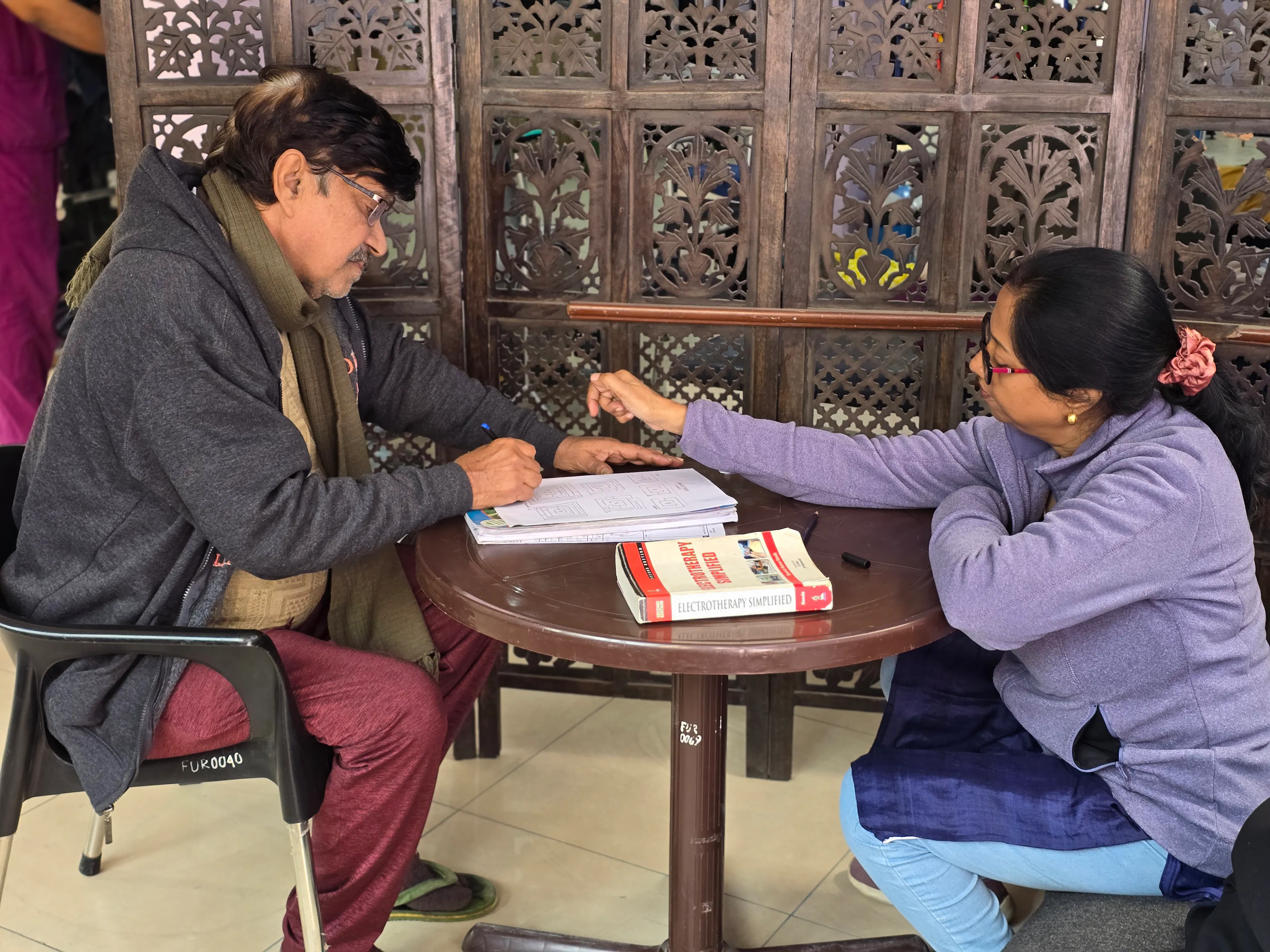 Therapist working through a language and writing worksheet with a man at a table