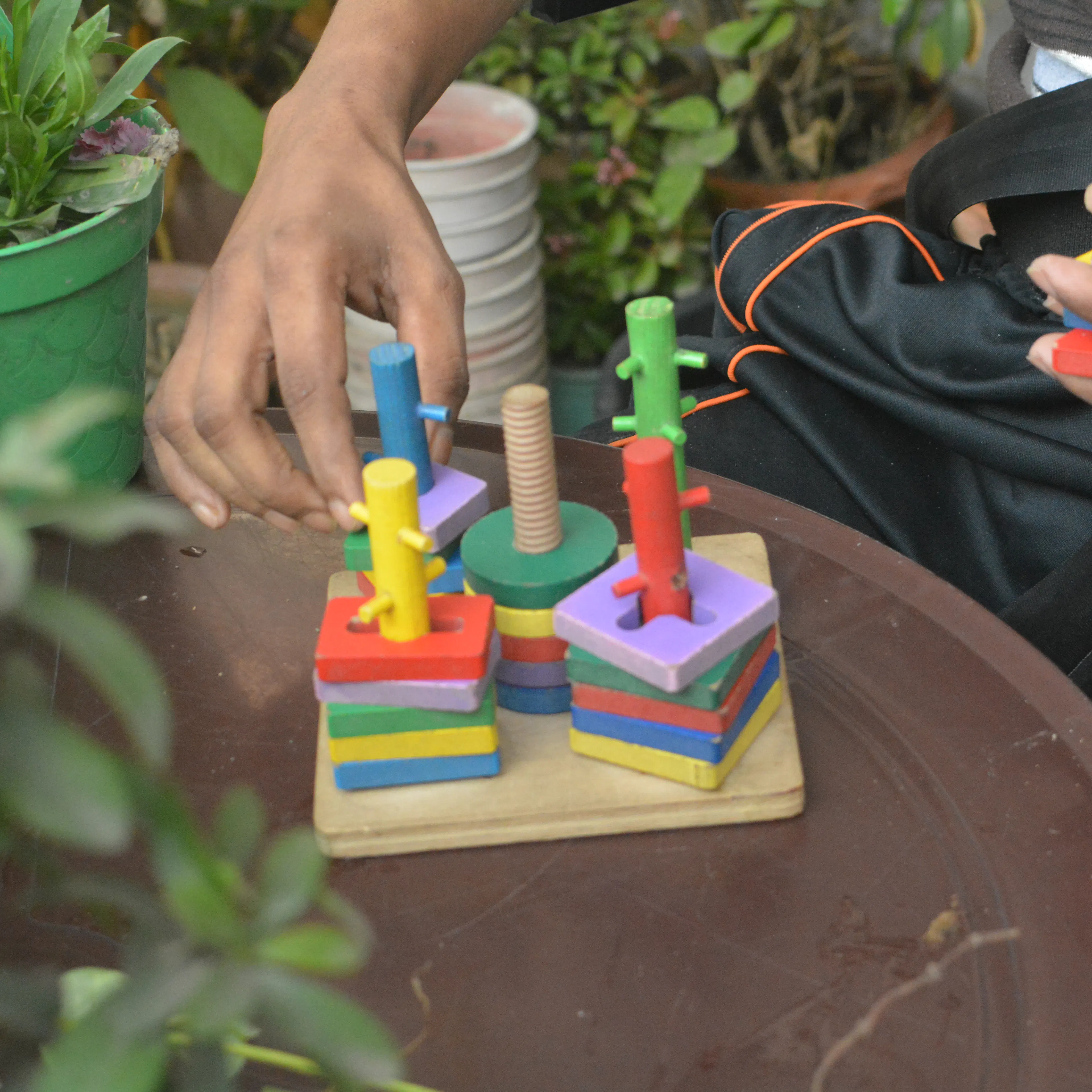 Patient doing a hand task outdoors among potted plants during a garden therapy session