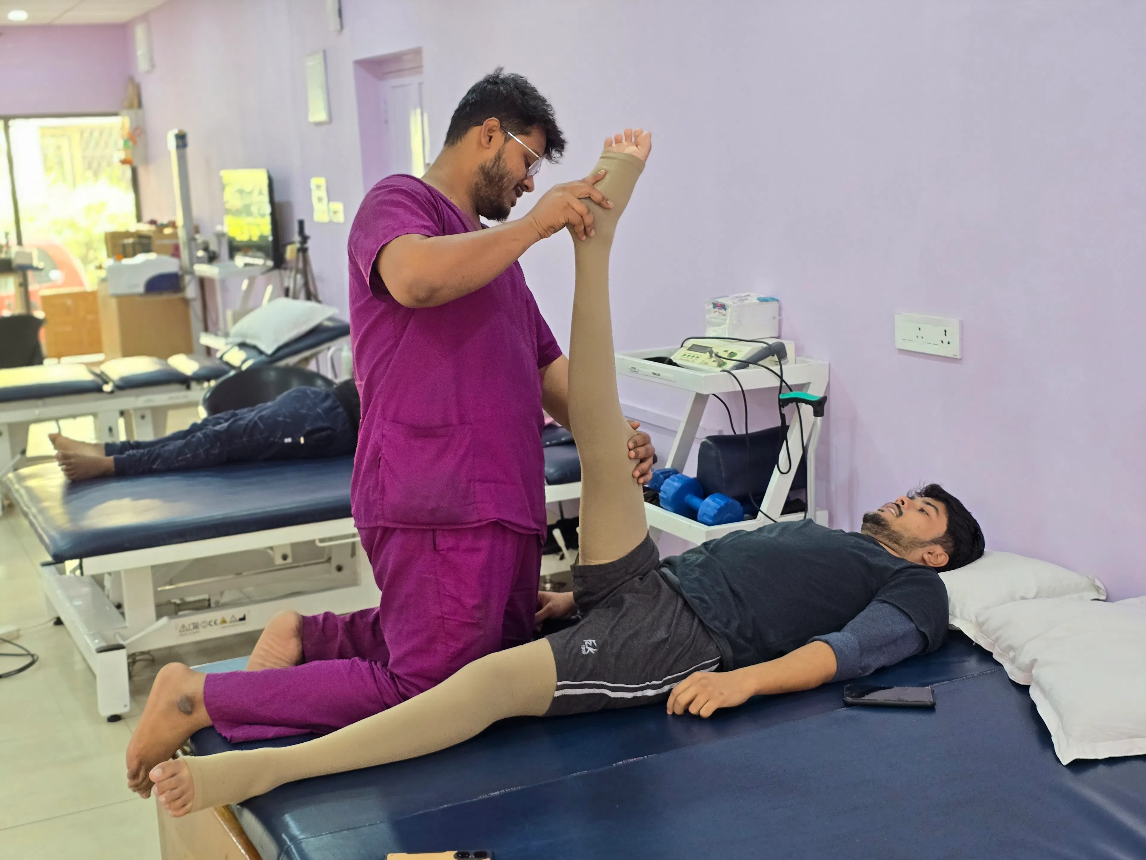 Physiotherapist stretching a patient's leg on a mat table during neuro physiotherapy