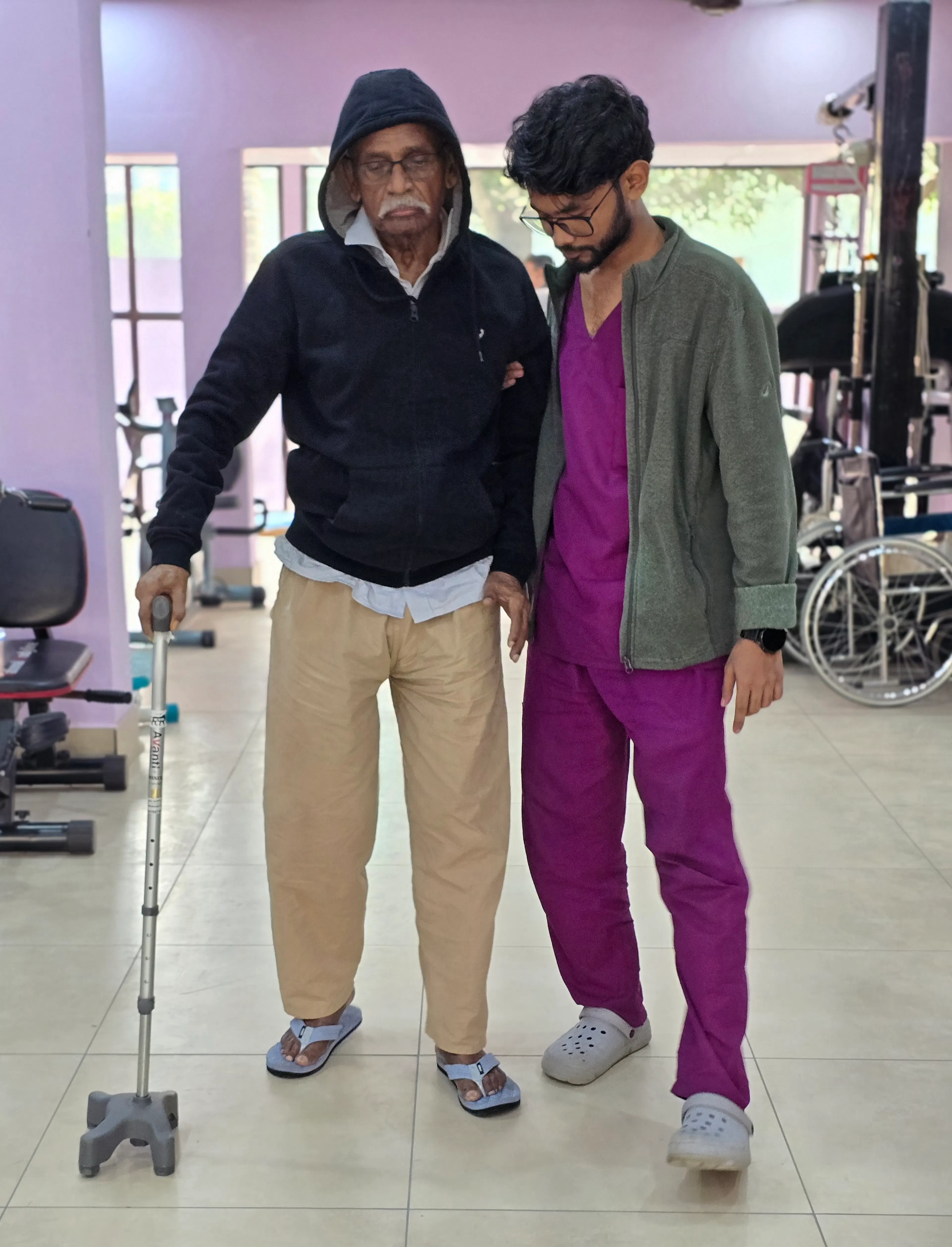Patient walking with a walking stick while a therapist walks beside him
