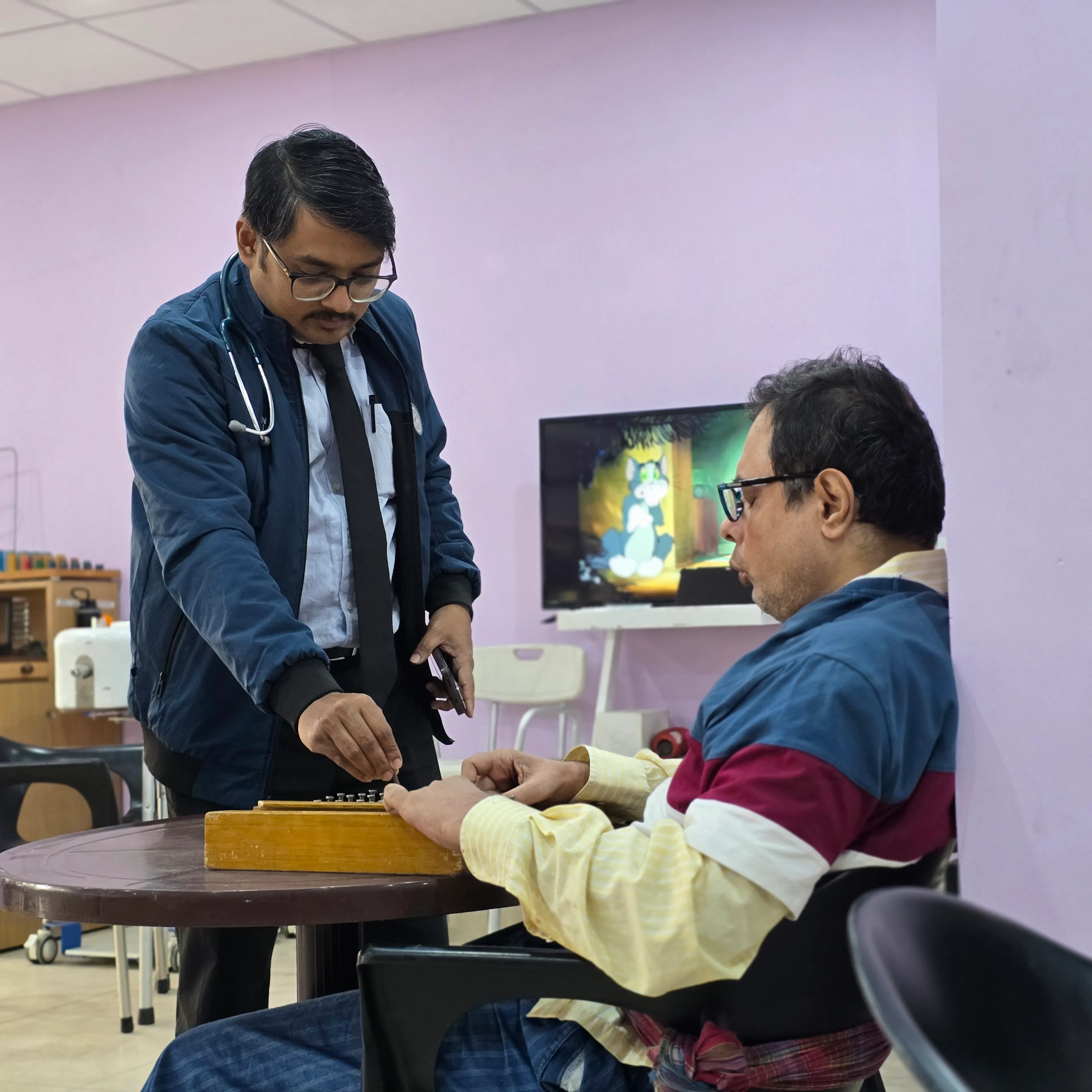 Doctor watching a patient do a hand task to review progress in occupational therapy