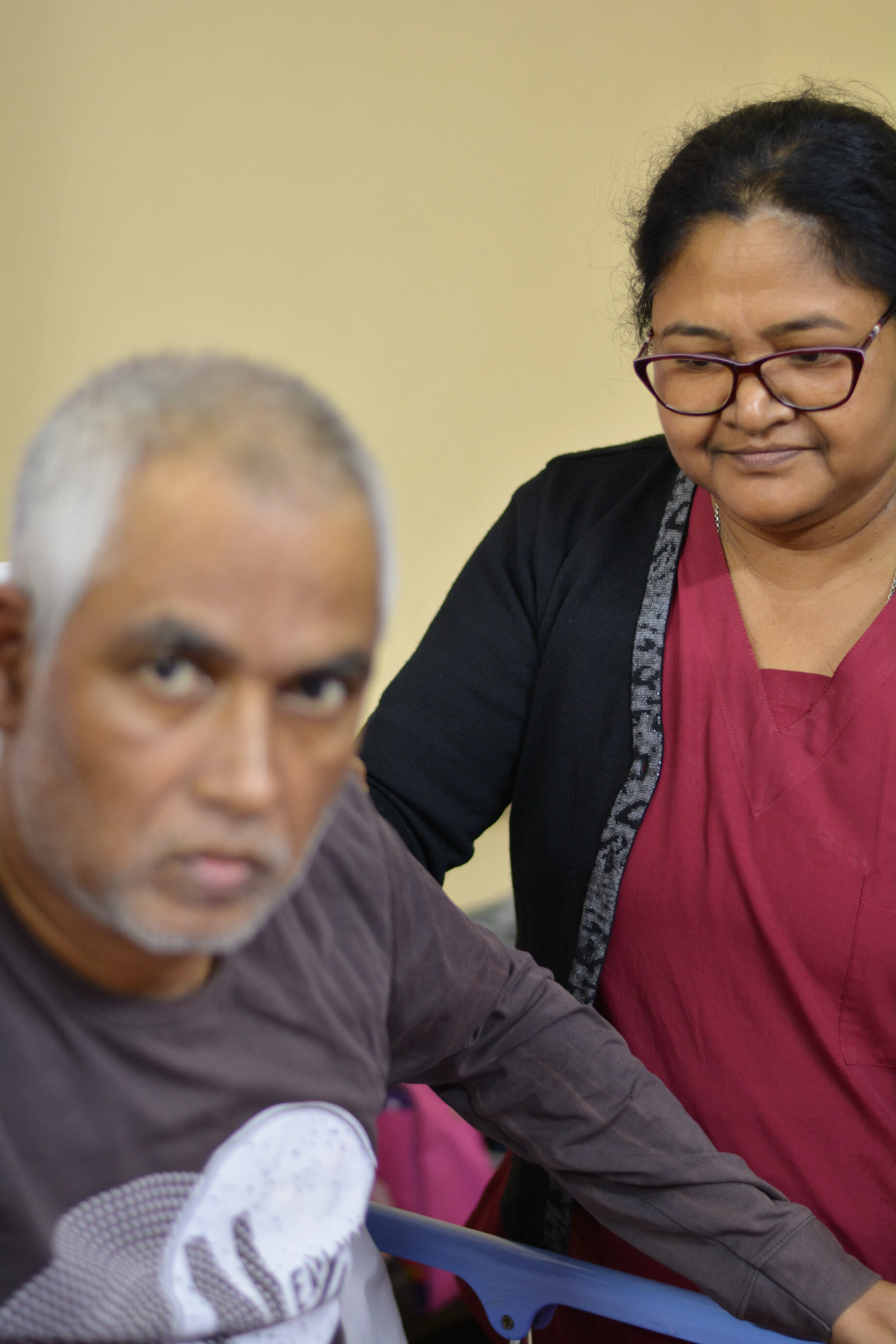 Family caregiver sitting close beside an elderly man to support his care at home
