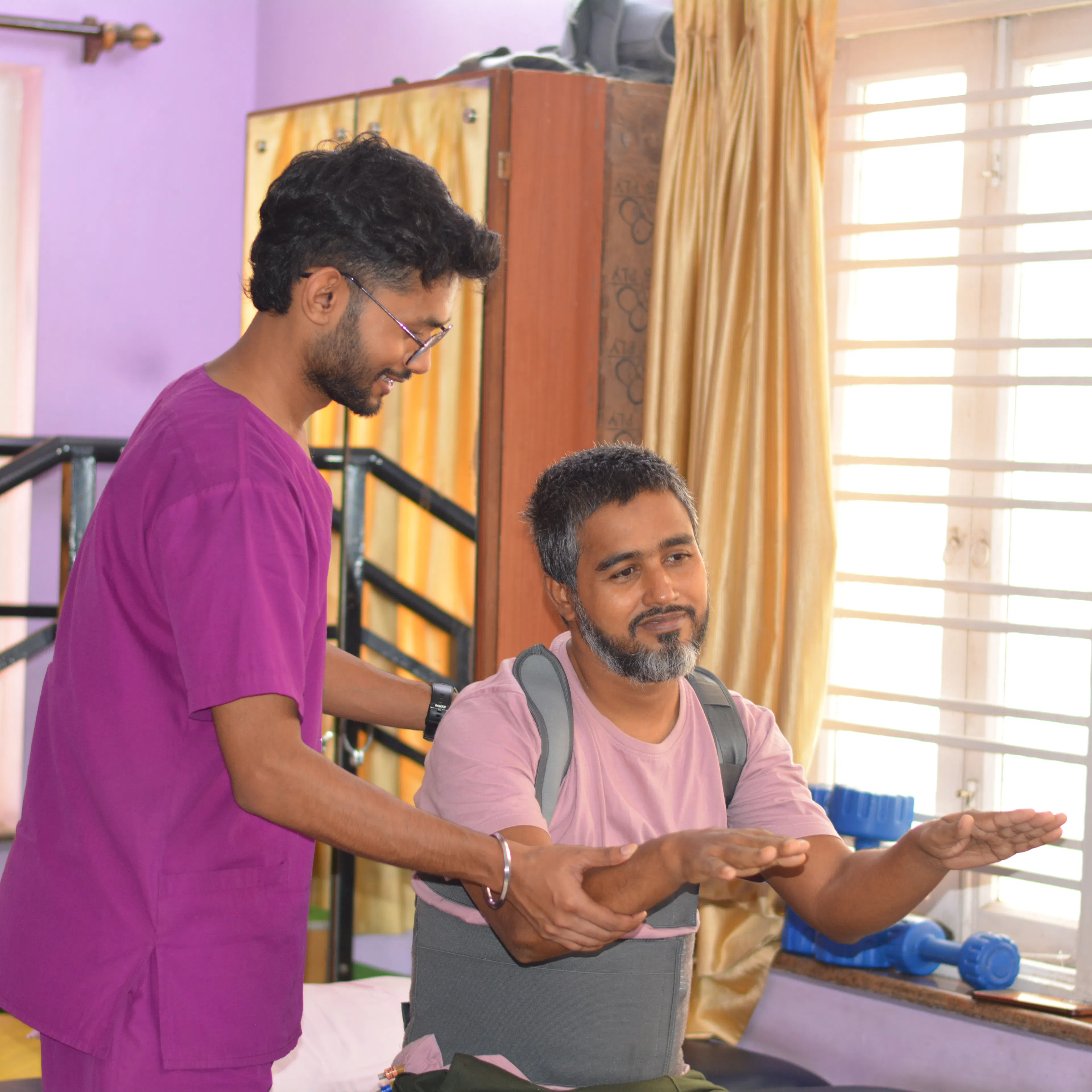 Physiotherapist guiding a seated man through arm exercises near parallel bars