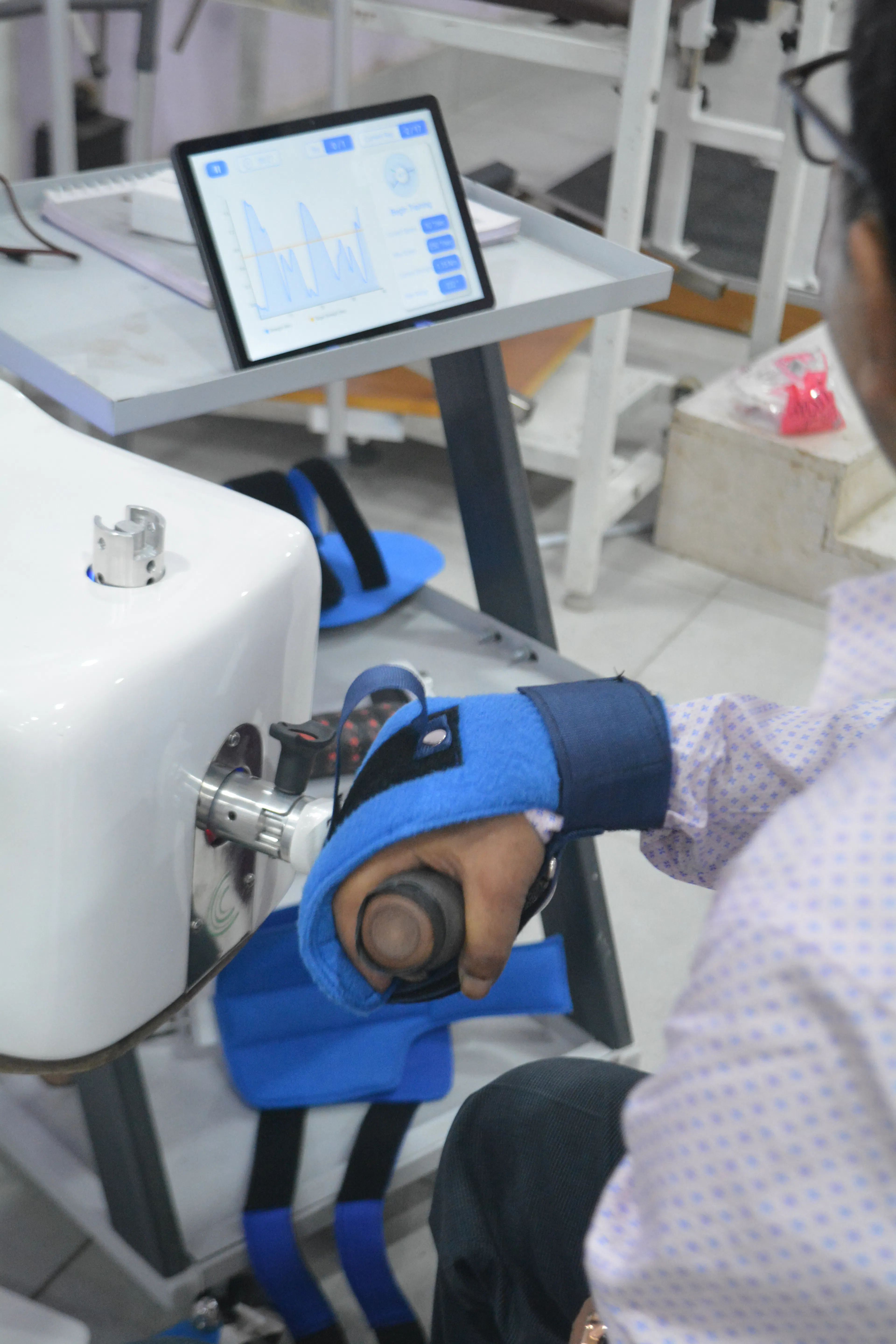 Hand and forearm placed in a robotic wrist and hand rehabilitation device with a tablet screen