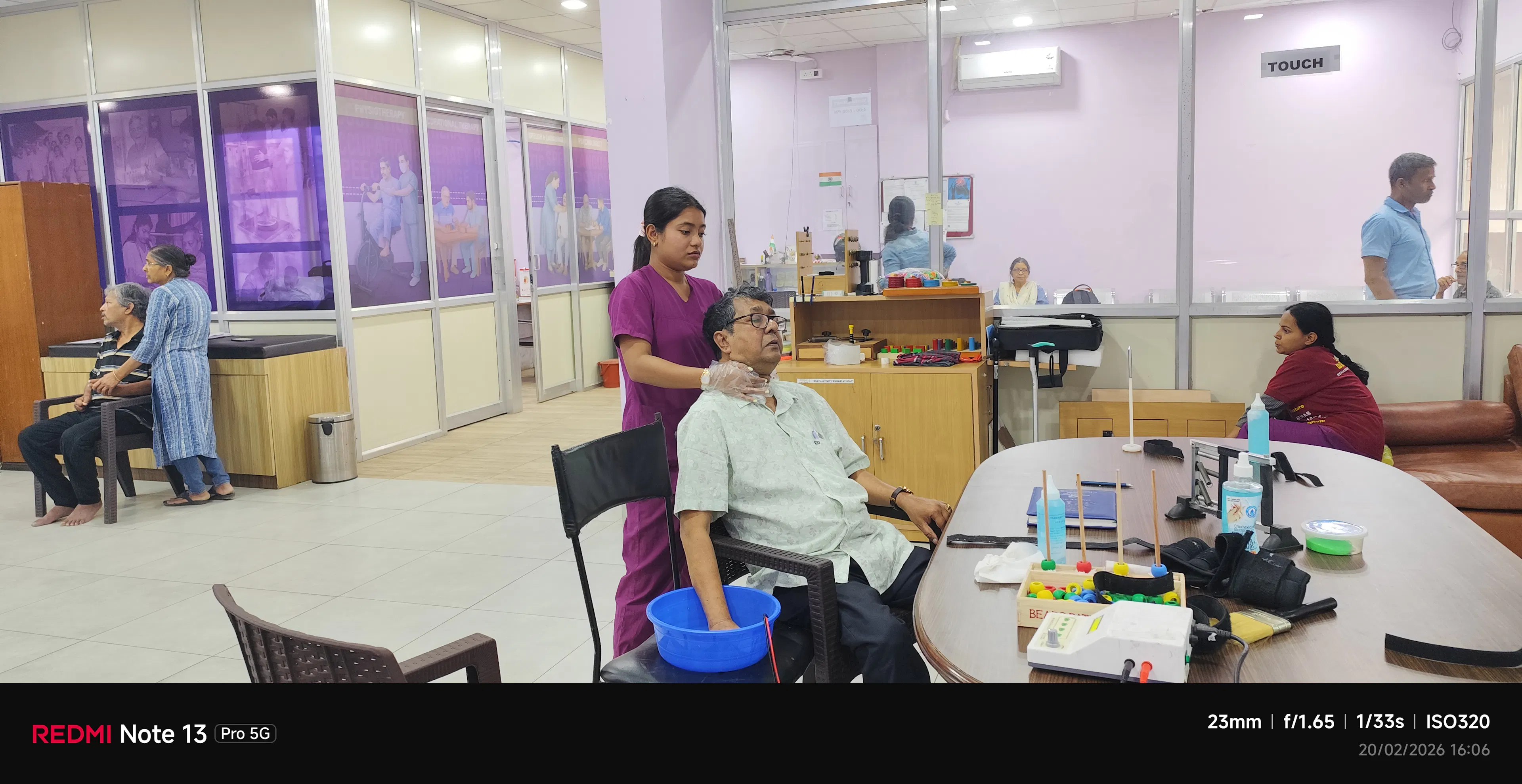Clinician talking with an older man on a sofa at home during a speech therapy visit