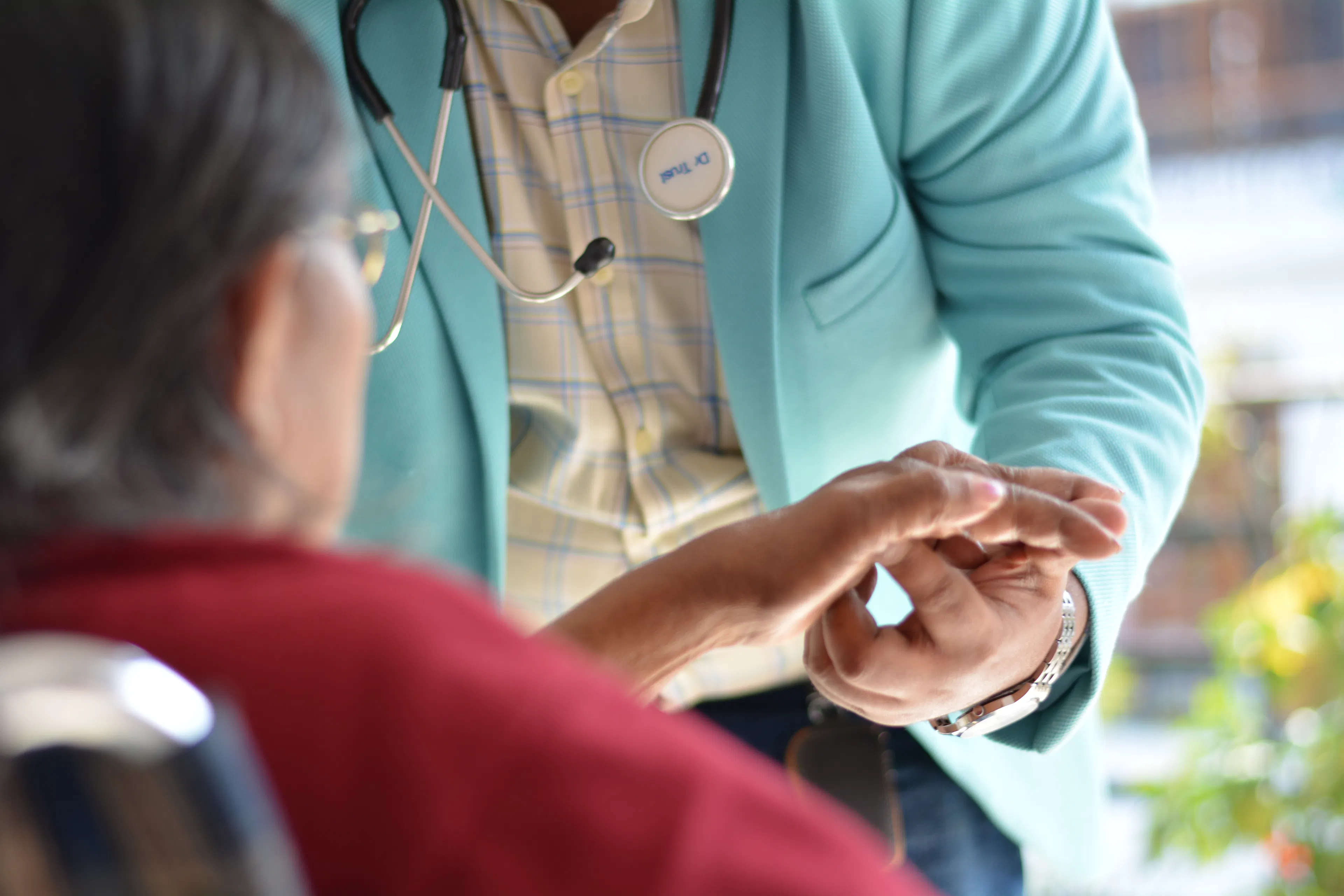 Doctor examining an older patient's hand and fingers during a first assessment before garden therapy
