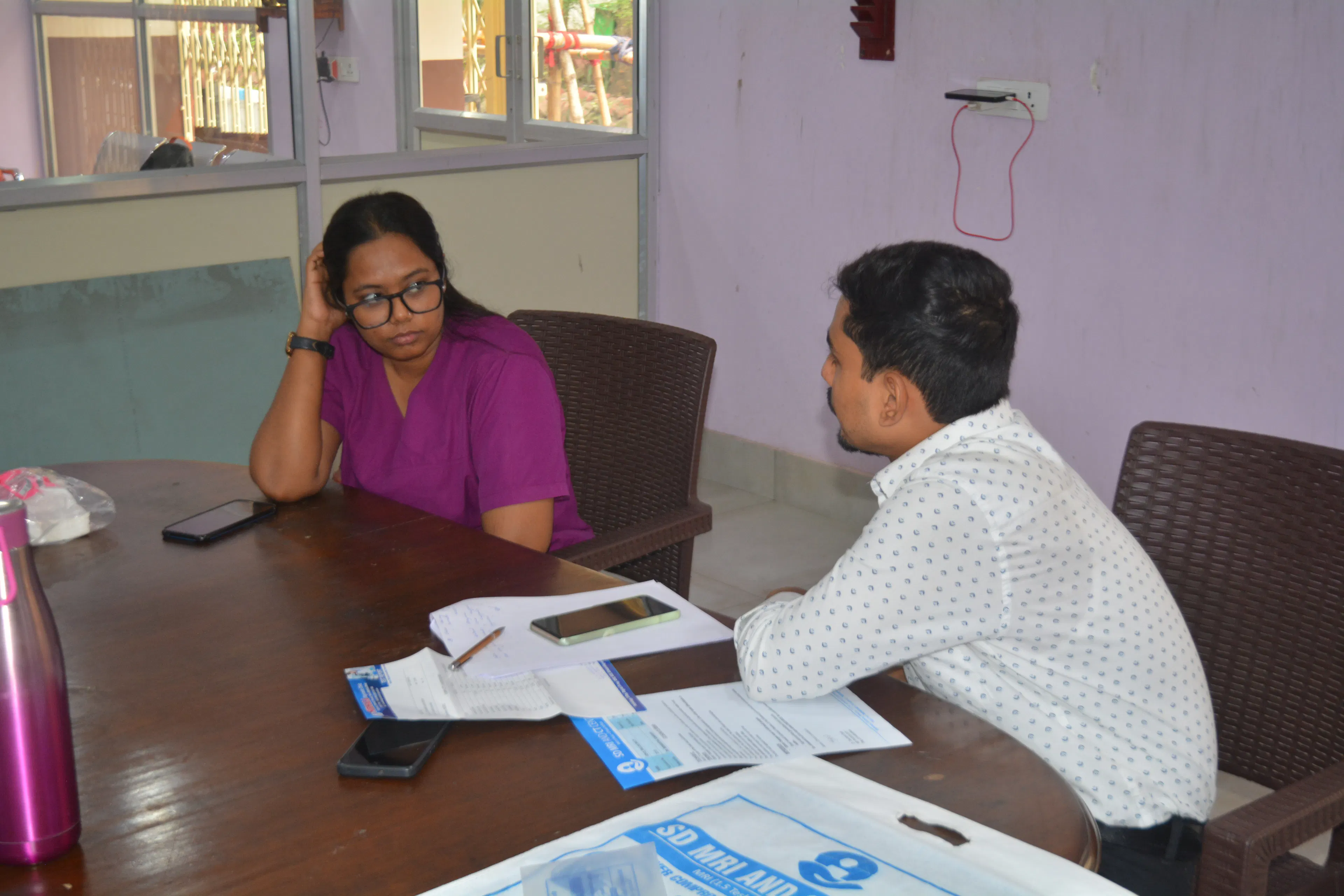 Clinician talking with a family member across a desk with papers