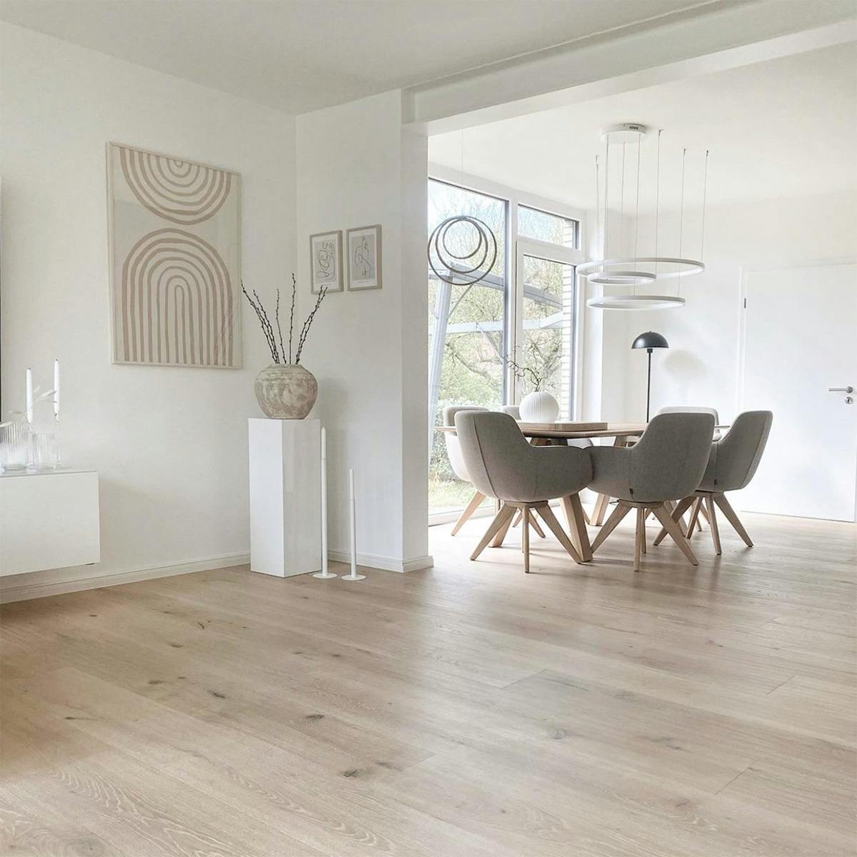 offenes Wohnzimmer kombiniert mit einem Esszimmer, Einrichtung in hellen Beigetönen, nordischer Stil, moderne Grafik an der Wand im skandinavischen Wohnzimmer