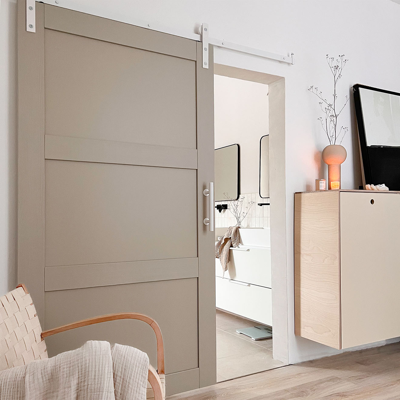 kieselgraue Tür an einem weißen Schiebesystem im Eingang zum Badezimmer