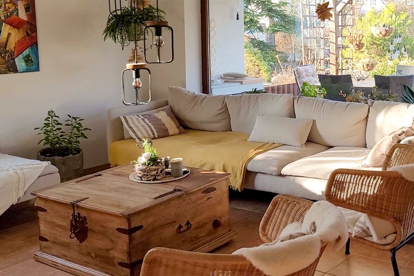 ein cremefarbenes Sofa, ein Truhentisch und Rattanstühle im Wohnzimmer