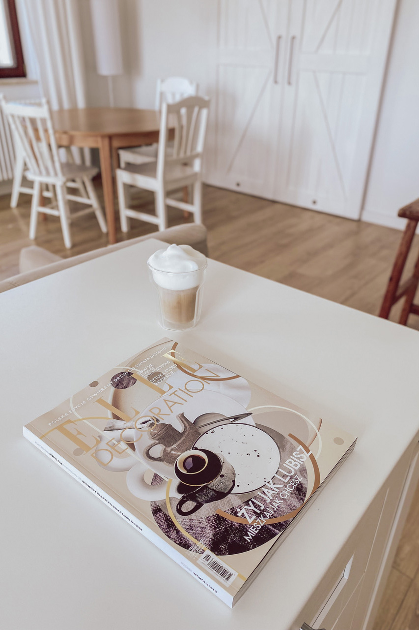 weiße große Kücheninsel, runder Tisch mit weißen Stühlen, offene Küche mit Essbereich