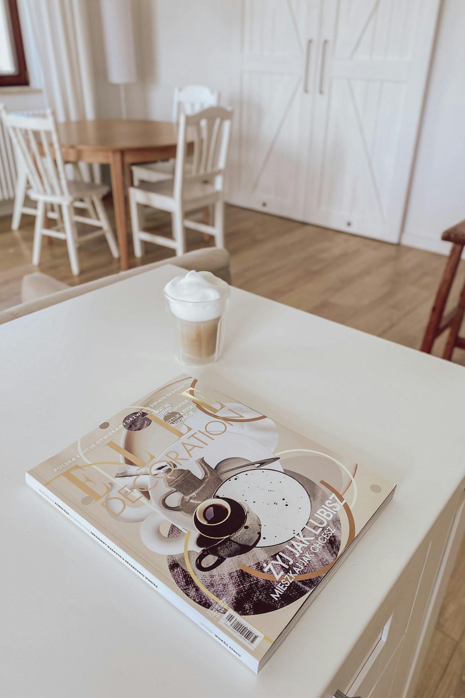 weiße große Kücheninsel, runder Tisch mit weißen Stühlen, offene Küche mit Essbereich