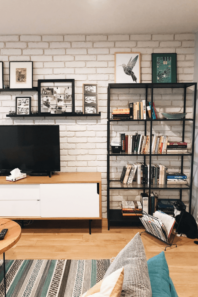 Innenraum im Industriestil, Backsteinmauer im Wohnzimmer, Bücherregal aus Metall, Wanddekorationen für das Wohnzimmer, Bilder für die Wand, Fernsehschrank im Industriestil