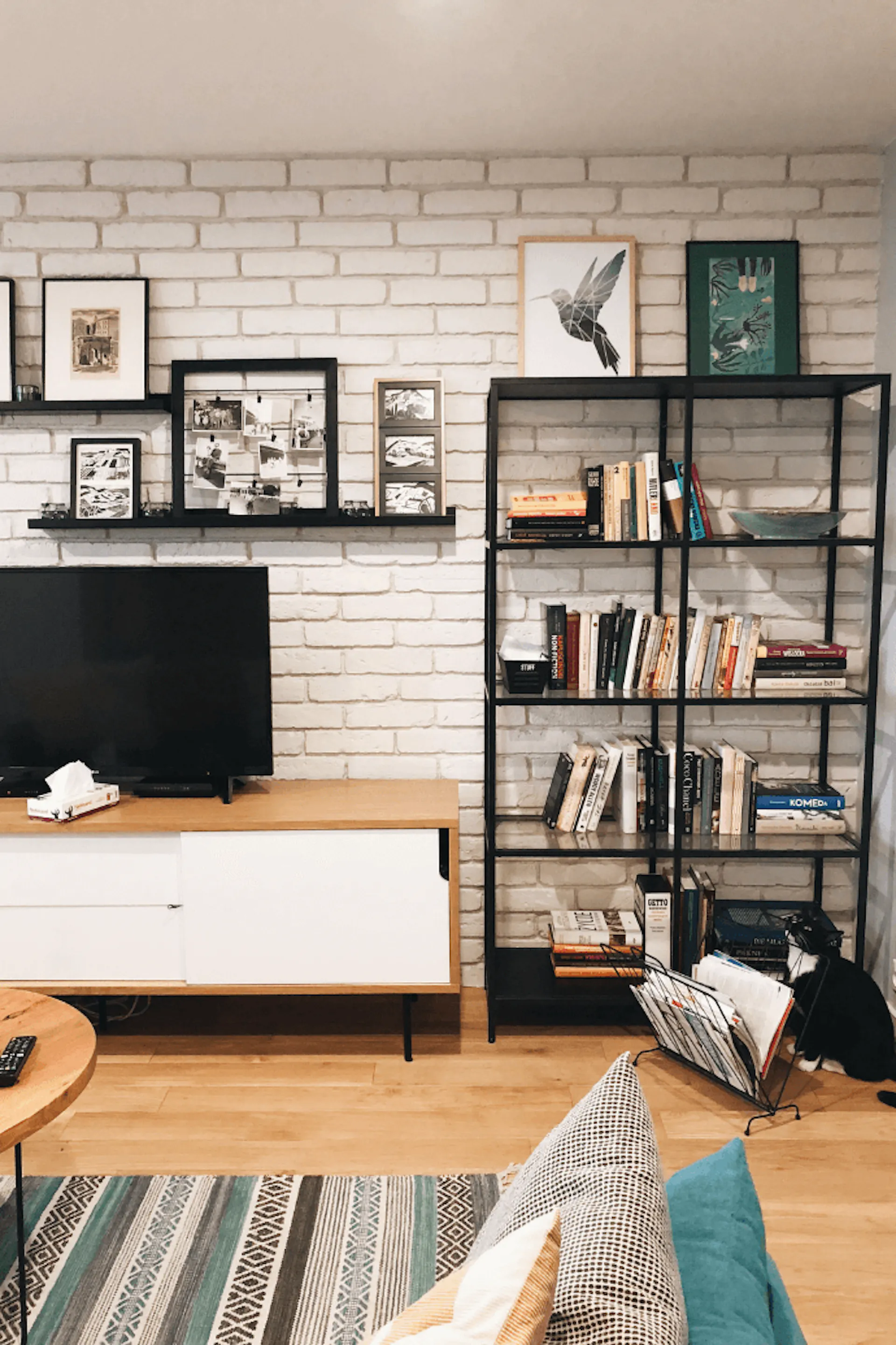 Innenraum im Industriestil, Backsteinmauer im Wohnzimmer, Bücherregal aus Metall, Wanddekorationen für das Wohnzimmer, Bilder für die Wand, Fernsehschrank im Industriestil