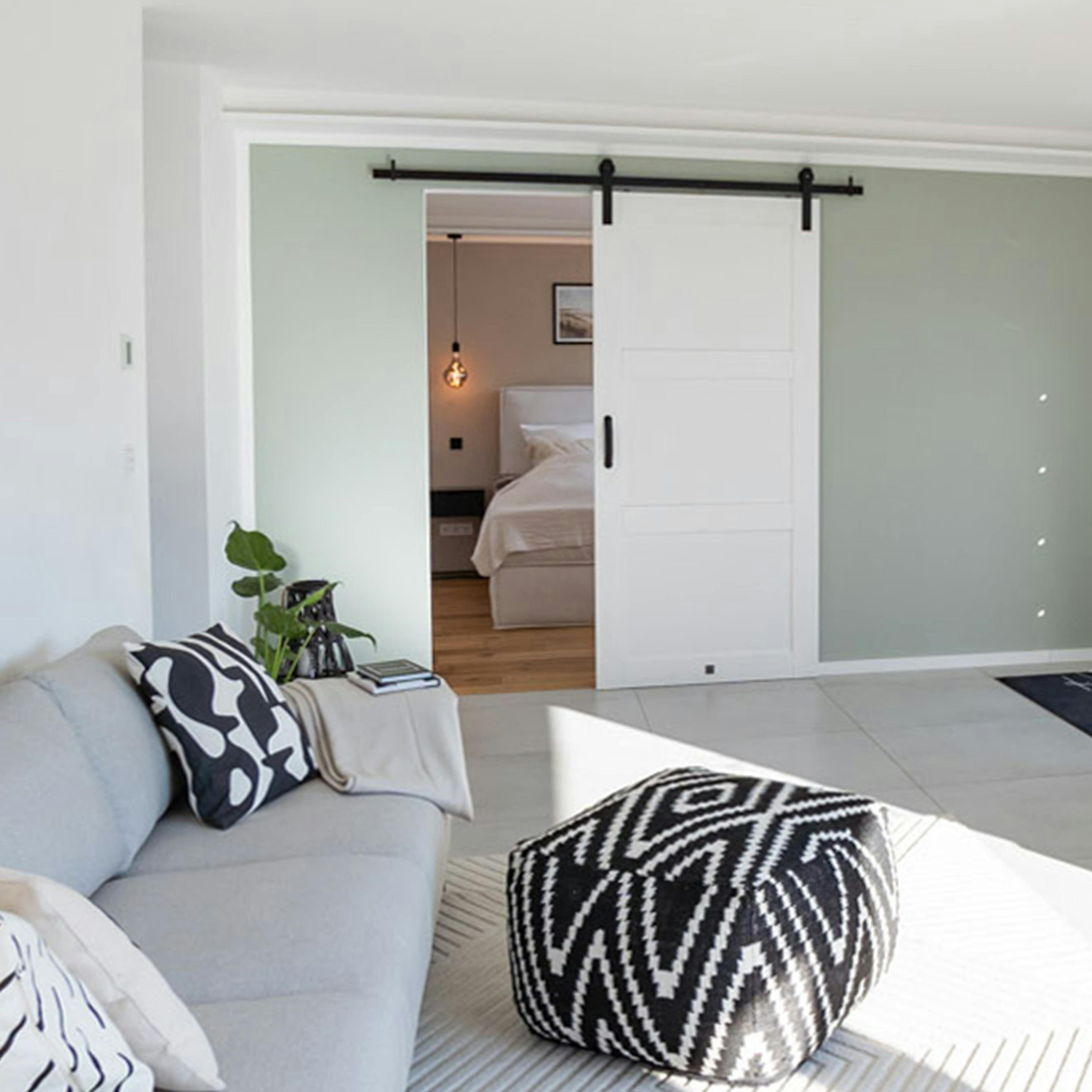 Moderne weiße Schiebetüren, graues Sofa, Puff mit geometrischen Mustern, minimalistische Dekorationen, modernes Wohnzimmer
