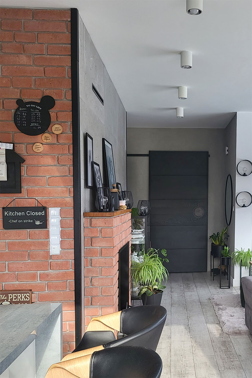 roter Backstein an der Wand und um den Kamin und schwarze Schiebetüren im Wohnzimmer