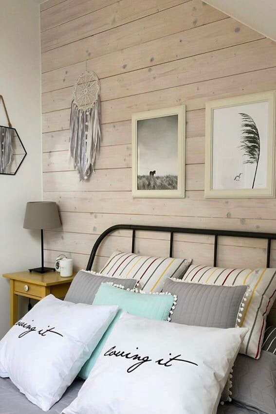 oreillers décoratifs sur le lit dans une chambre décorée dans des tons pastel