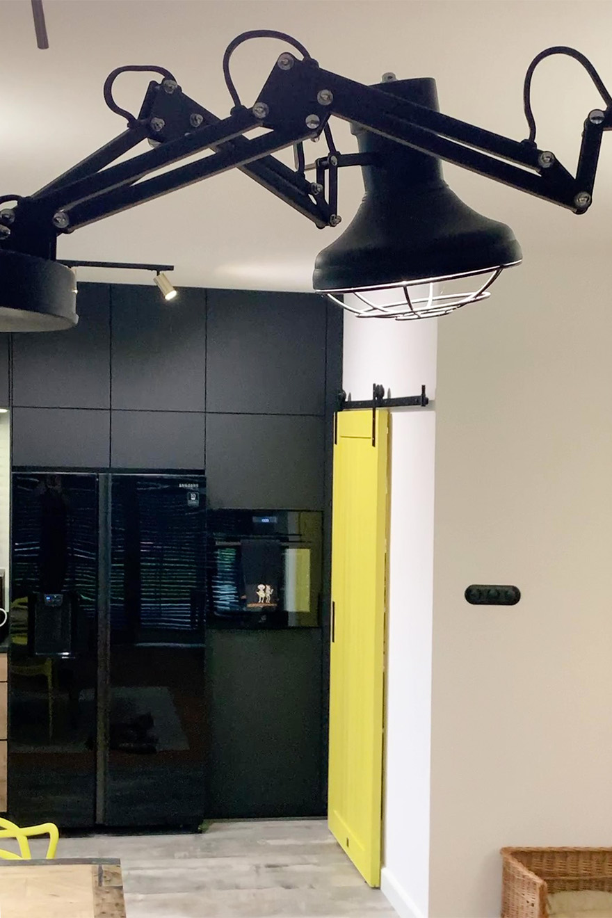 czarna industrialna lampa wisząca i żółte drzwi przesuwne w nowoczesnym wnętrzu