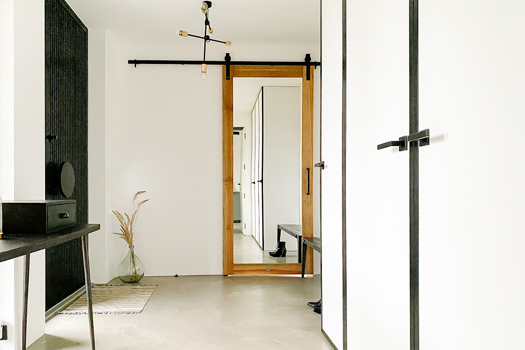 Industrialna lampa, czarny minimalistyczny stolik i drzwi przesuwne z lustrem w wiatrołapie