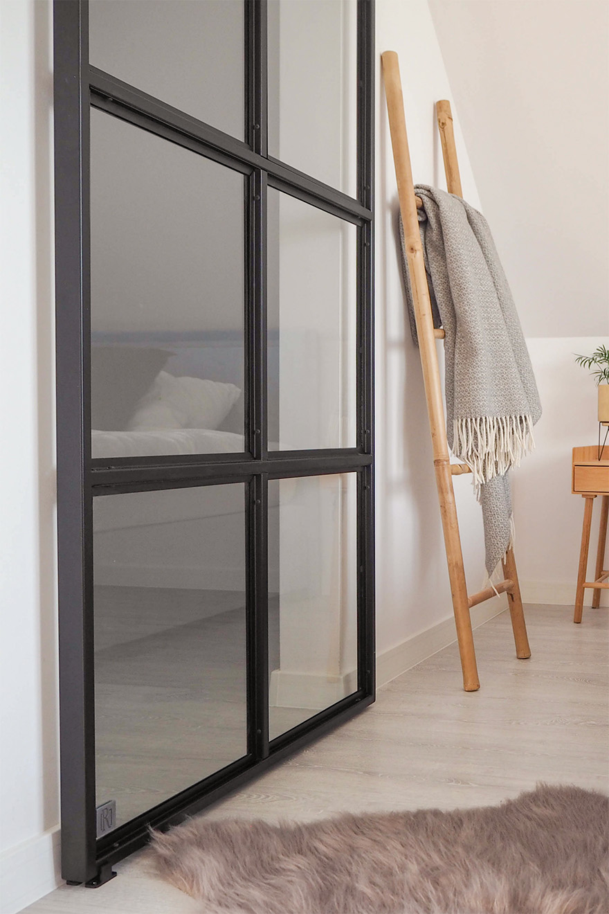 szklane drzwi przesuwne w czarnej metalowej ramie w wejściu do garderoby na poddaszu