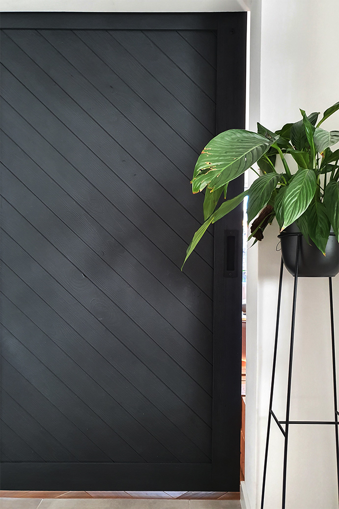 schwarze Schiebetür, hoher Metall Blumenständer