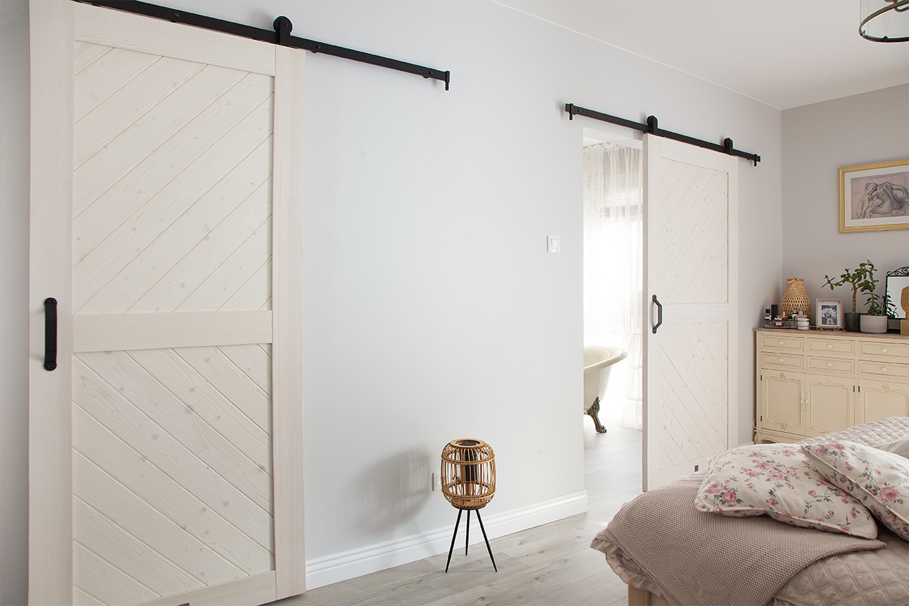 weiße Schiebetür zum Badezimmer in einem im provenzalischen Stil eingerichteten Schlafzimmer