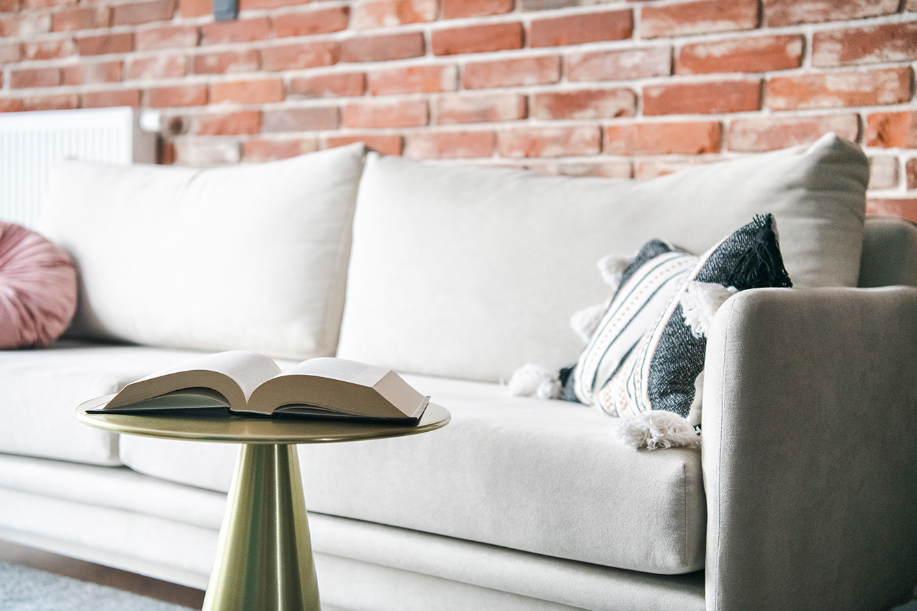 jasna sofa i czerwona cegła na ścianie w salonie