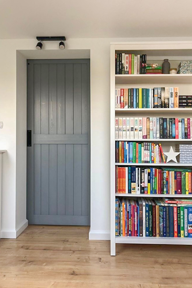 une porte en bois grise à côté d'une étagère blanche