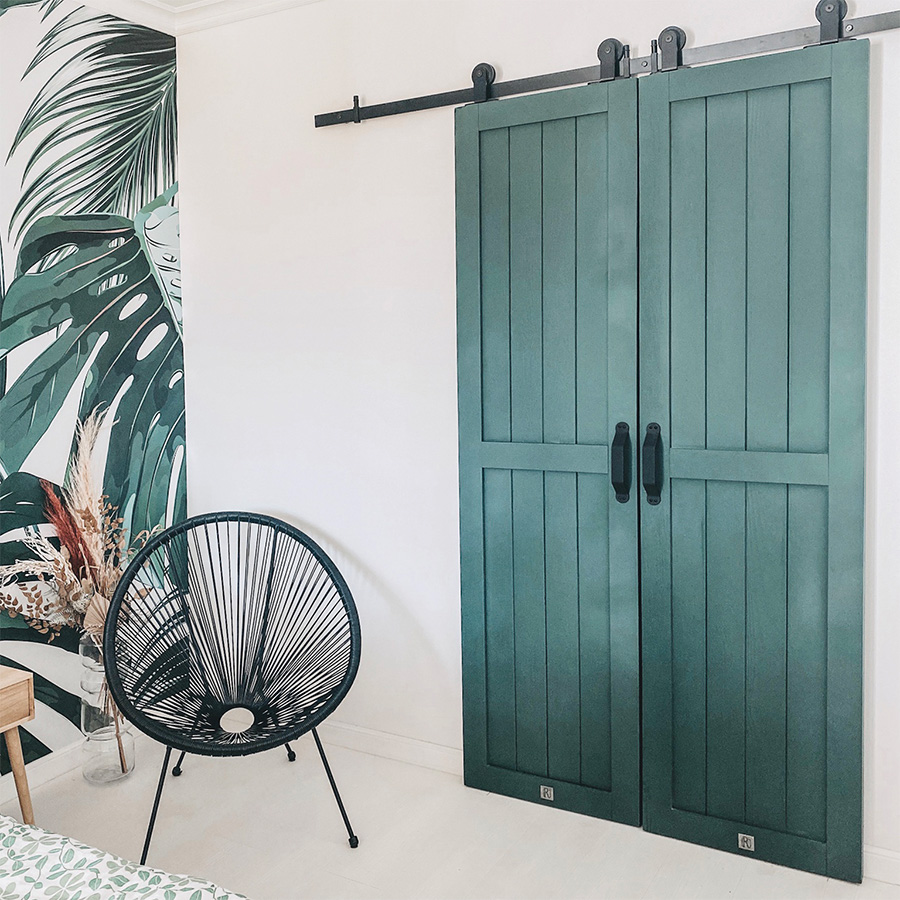 grüne Türen, begehbare Kleiderschrank Tür, Schiebetür, schwarzes Schiebetürsystem, schwarzer durchbrochener Sessel, Massivholztür, Weiß und Grün im Schlafzimmer, botanische Tapete, Pflanzentapete