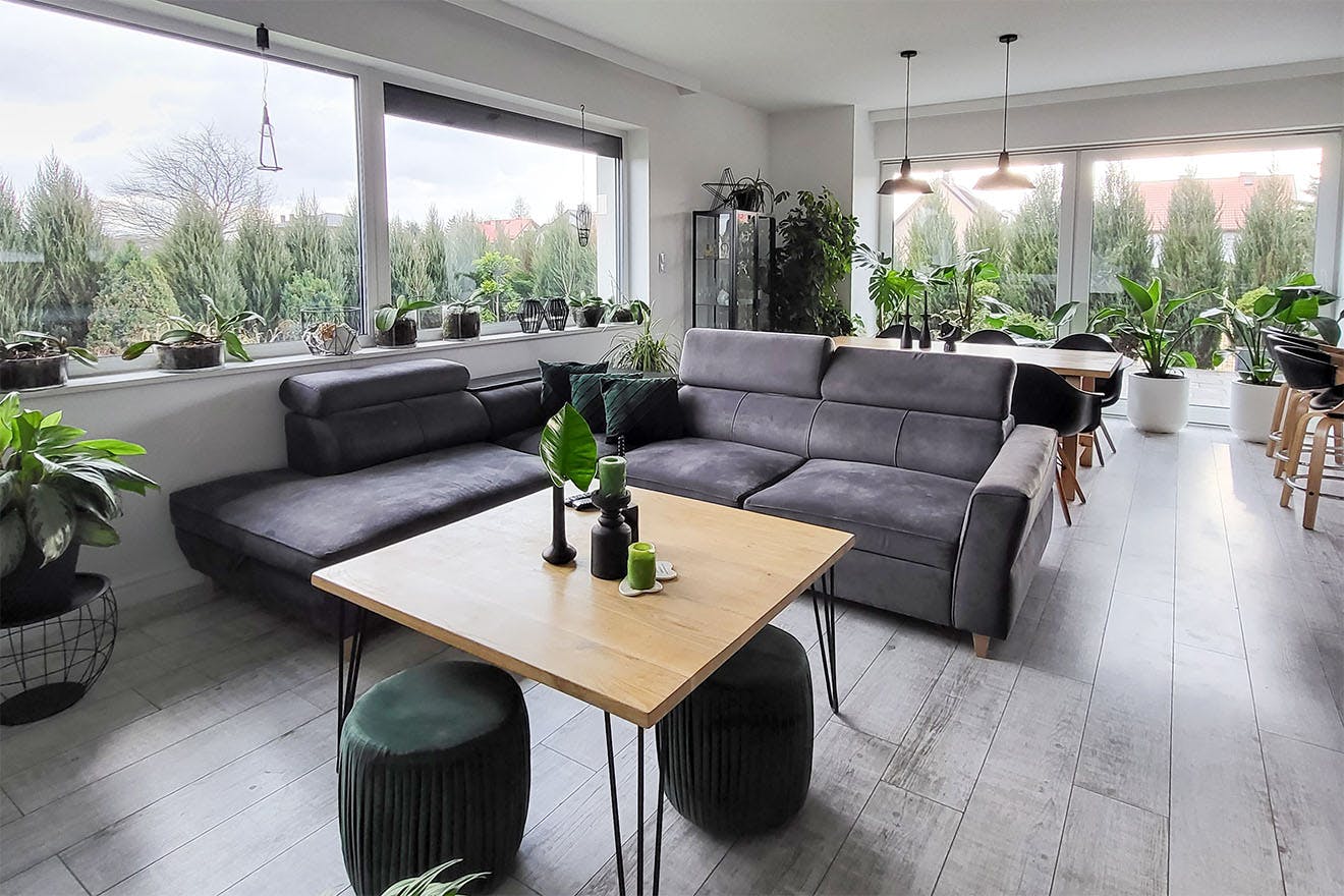 ein Wohnzimmer mit einem grauen Sofa und einem quadratischen Couchtisch aus Holz in einem grau-schwarzen Arrangement