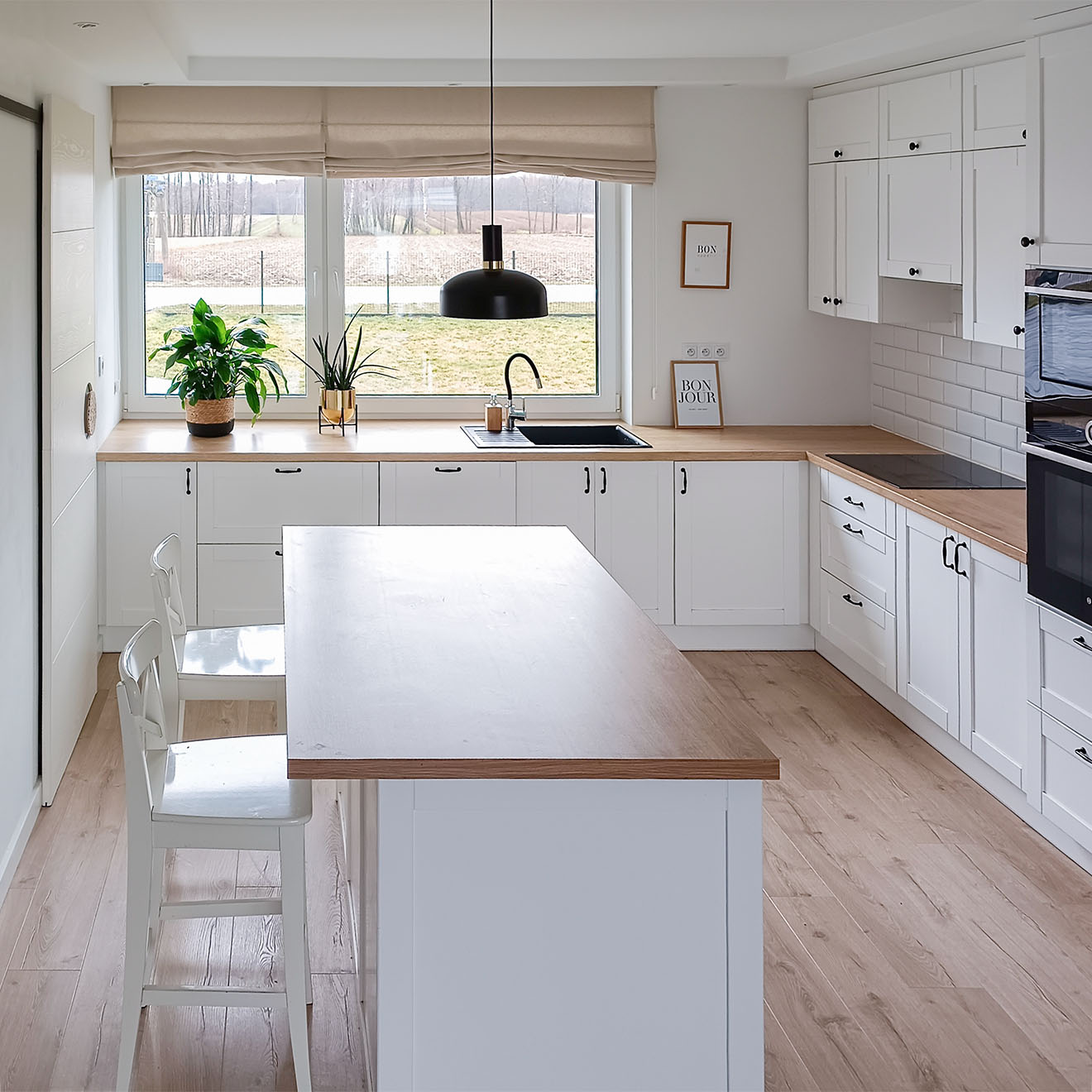 kuchnia z wyspą wykończona w bieli i drewnie