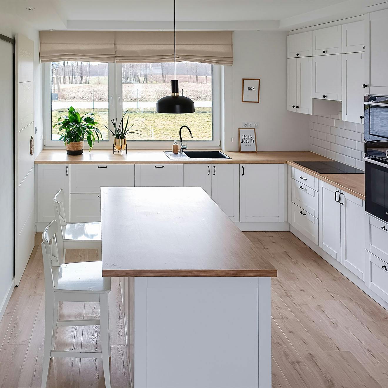 kuchnia z wyspą wykończona w bieli i drewnie