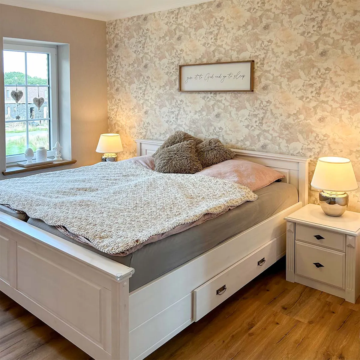 duże łóżko przy ścianie z kwiecistą tapetą w sypialni urządzonej w stylu modern farmhouse