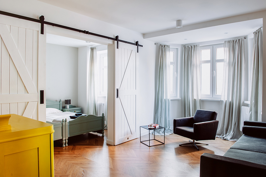 weiße Doppelschiebetüren, die das Wohnzimmer und das Schlafzimmer in der Mietwohnung trennen